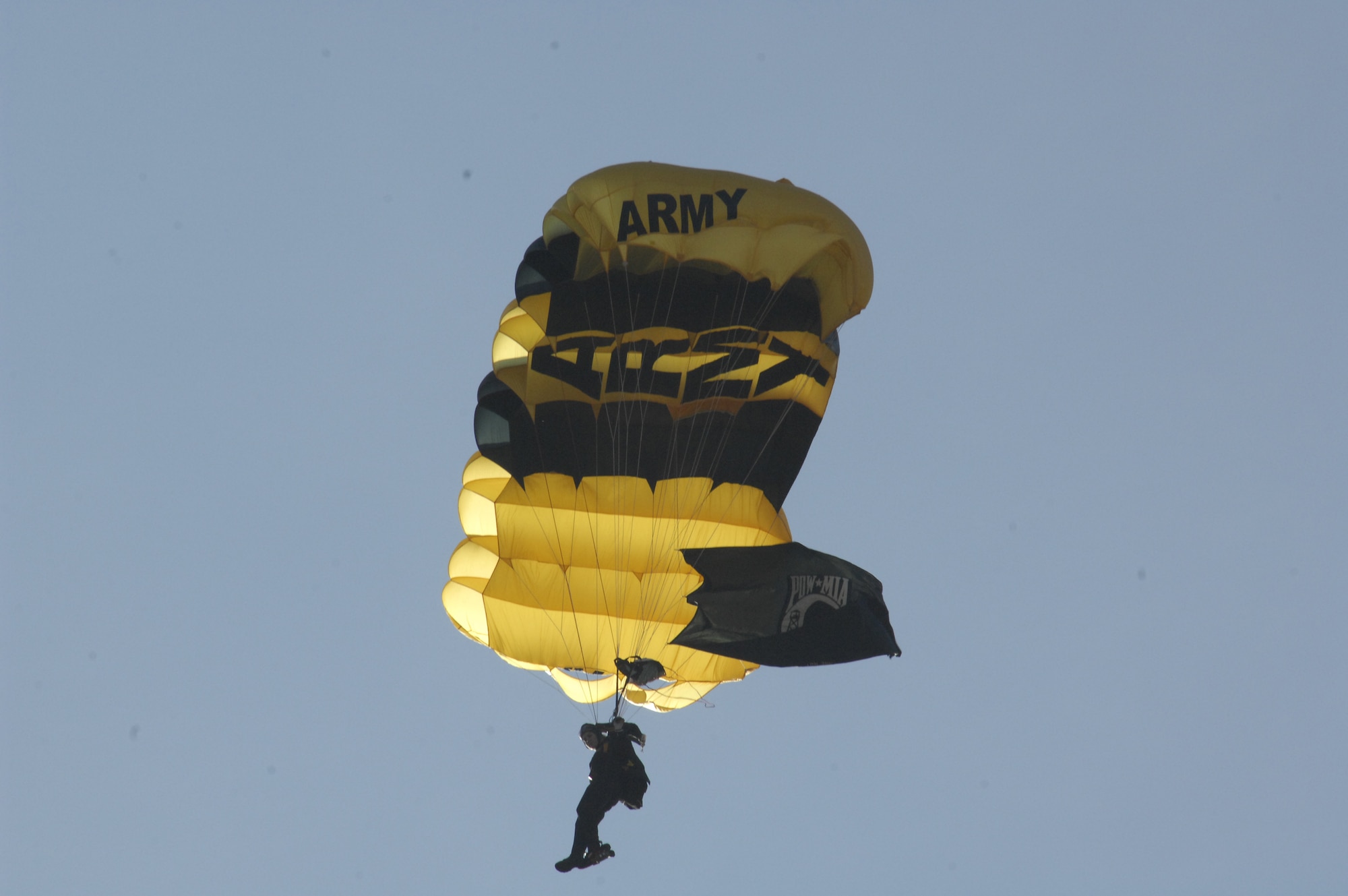 MINOT AIR FORCE BASE, N.D. -- A U.S. Army Golden Knight parachute team member descends on Minot with the P.O.W flag unfurled during the 2009 Northern Neighbors Day festivities here July 18. Thousands of people turned out to watch the 2009 Northern Neighbors Day, which came through on its promise to wow spectators with amazing aerial maneuvers, nail-biting choreography, historic displays and much more. (U.S. Air Force Photo by Airman 1st Class Jesse Lopez)