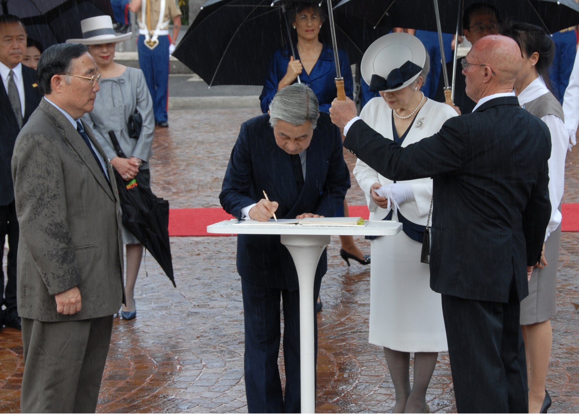 Emperor Akihito and Empress Michiko sign the guest book July 15 at the National Memorial Cemetery at Punchbowl Crater, Hawaii. The Imperial couple lay a wreath to honor the more than 50,000 service men and women interred at the cemetery. (U.S. Air Force photo/Staff Sgt. LuCelia Ball)