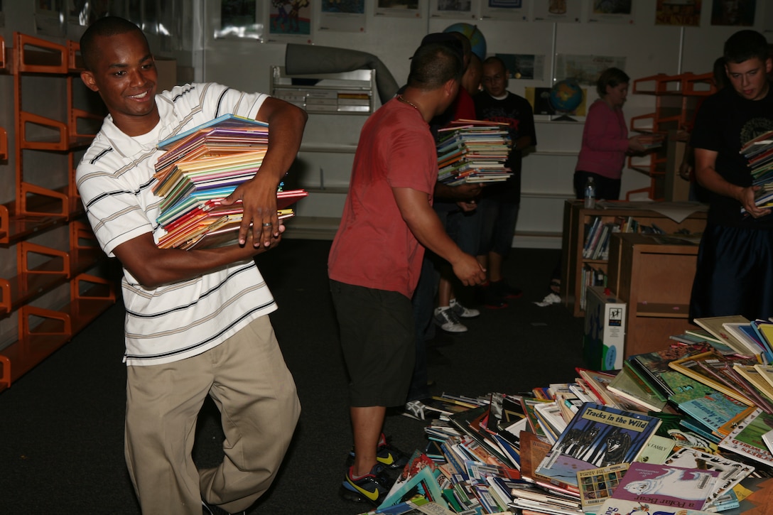 Cpl. Ceariaco P. Cabrellis a legal clerk with Headquarters and Headquarters Squadron aboar the air station takes books off shelves from the library at Mason Elementary School. The Marines and sailors from the air station assisted the school's faculty by moving desks, cabinets and computers from classroom to classroom.