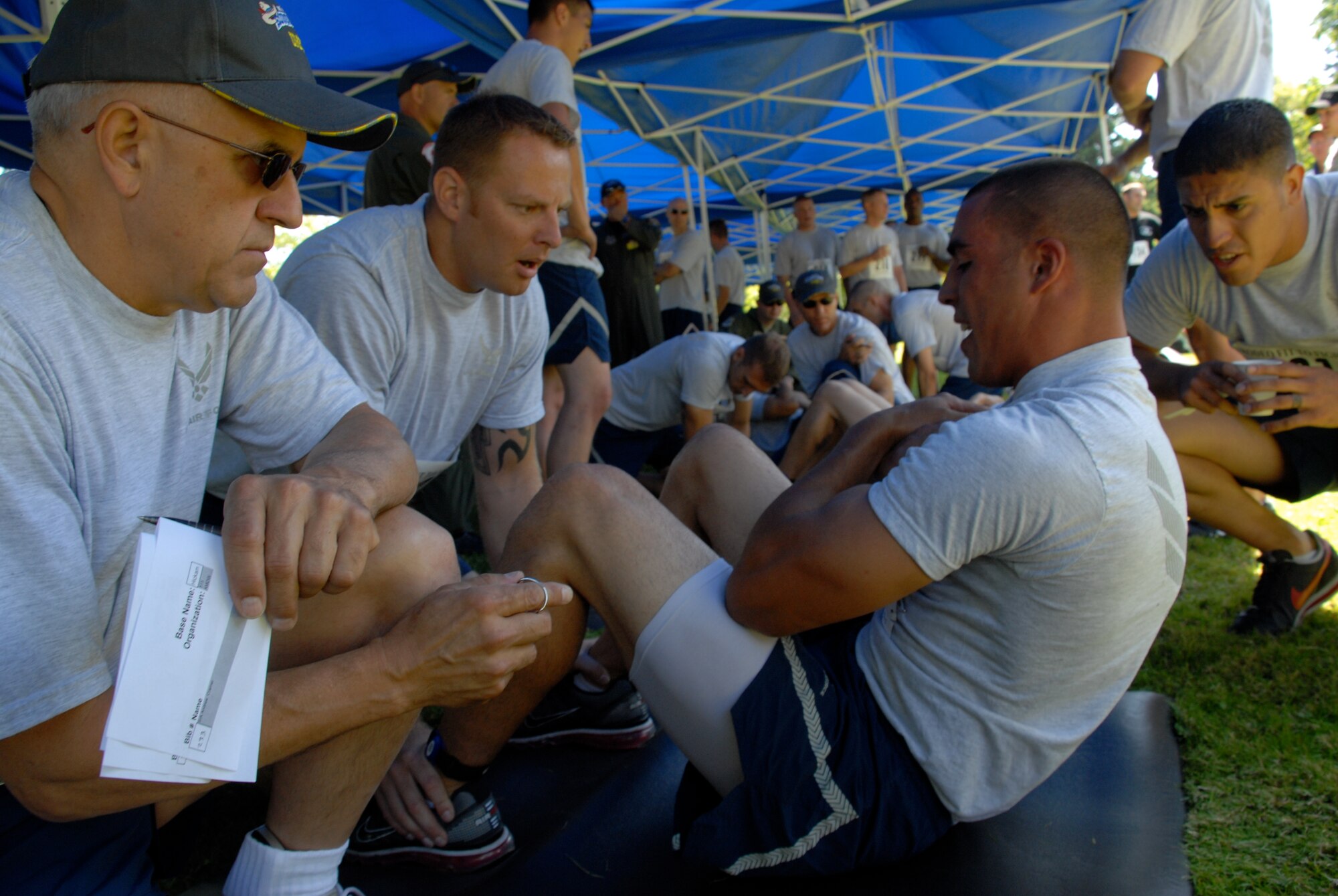 MCCHORD AIR FORCE BASE, Wash. -- Senior Airman Andrew Cramer, 732th Air Mobility Squadron, Elmendorf Air Force Base, Alaska, performs sit-ups for a physical fitness test at the Air Mobility Rodeo 2009. His 515th Air Mobility Operations Wing teammates Staff Sgt. Travis Wilt, 733rd Air Mobility Squadron, Kadena Air Base, Japan (to his left) and Senior Airman Baltazar Valdez, 731st Air Mobility Squadron, Osan Air Base, Korea, encouraged each other during the competition McChord Air Force Base, Wash. All three are aerial porters, part of a Pacific team which trained at Hickam Air Force Base, Hawaii, and joined with the 15th Airlift Wing for the Rodeo. This elite group of Airmen was hand-picked from more than 500 other aerial porters in the Pacific to compete. (U.S. Air Force photo/Staff Sgt. Carolyn Viss)