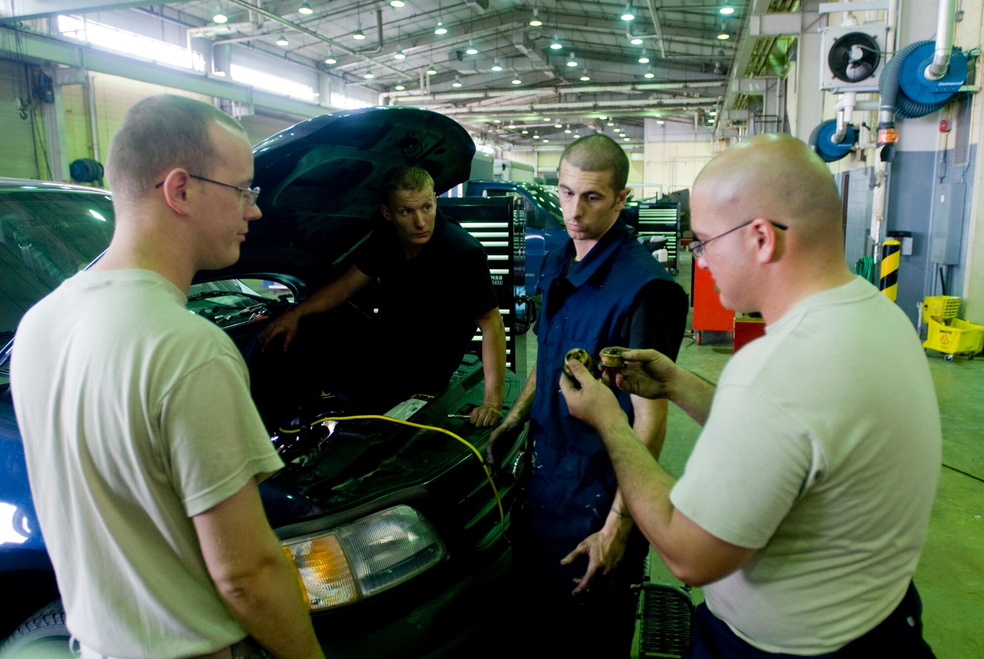 Senior Airman Phillip Earwood holds up two thermostats to the other mechanics for comparison at Kunsan Air Base, Republic of Korea July 16. Airman Earwood is a vehicle maintainer from the 8th Logistics Readiness Squadron, who is responsible for the upkeep of all vehicles on Kunsan Air Base. (U.S. Air Force Photo/Senior Airman Jonathan Steffen)