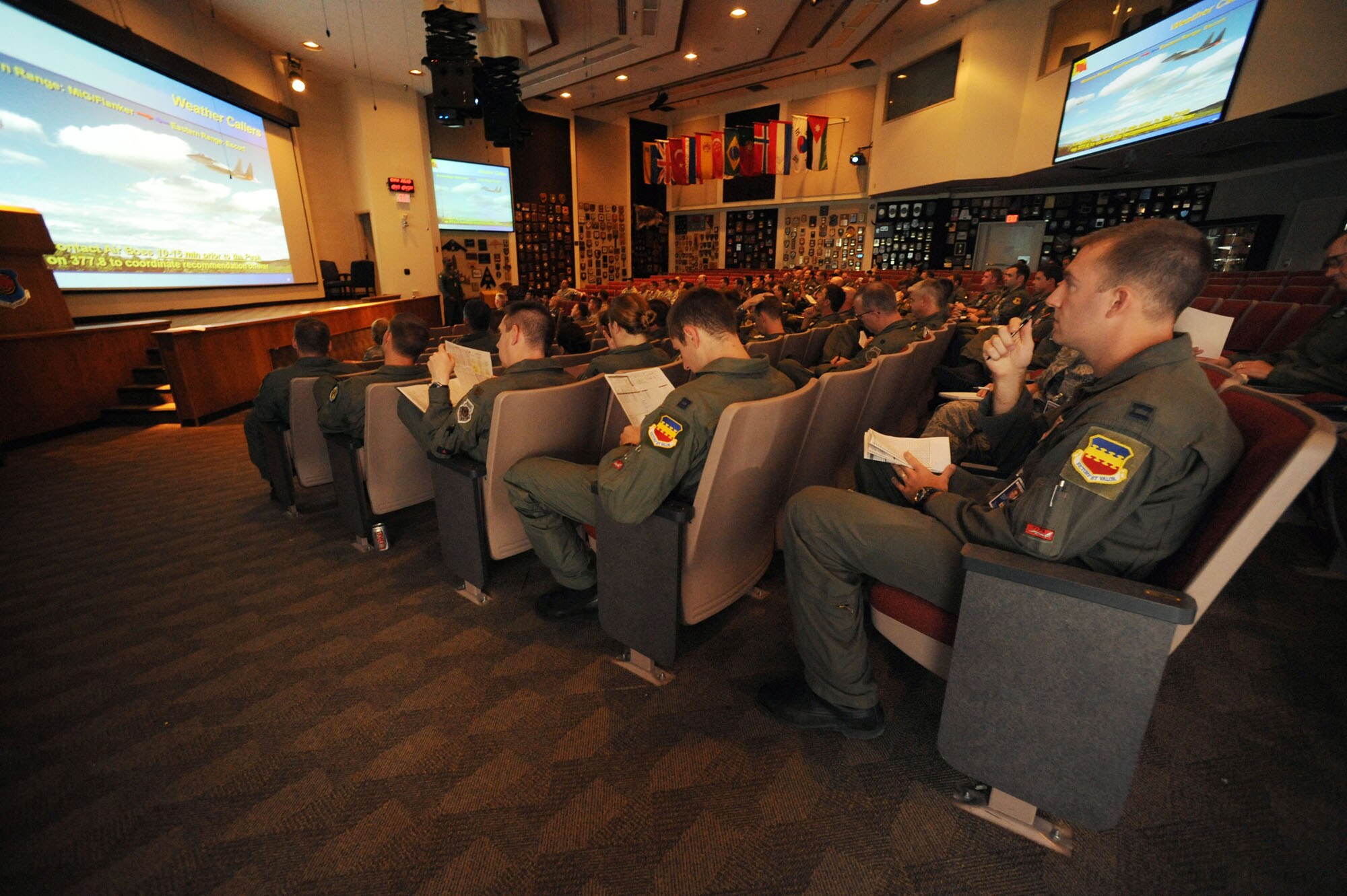 Capt. Taylor Blevins, 77th Fighter Squadron sits in the mass briefing facility with approximately 50 U.S. and allied nation pilots  at , Nellis Air Force Base, Nev.,  July 16, 2009, during Red Flag 09-4 . Mass briefings can last more than an hour and provide pilots with vital information for their simulated combat scenarios. Red Flag is a highly-realistic combat training exercise that pits U.S. and allied nation air forces against 'enemy' forces in a challenging air, ground, cyberspace and electronic threat environment. (U.S. Air Force Photo/Tech. Sgt. Michael R. Holzworth)