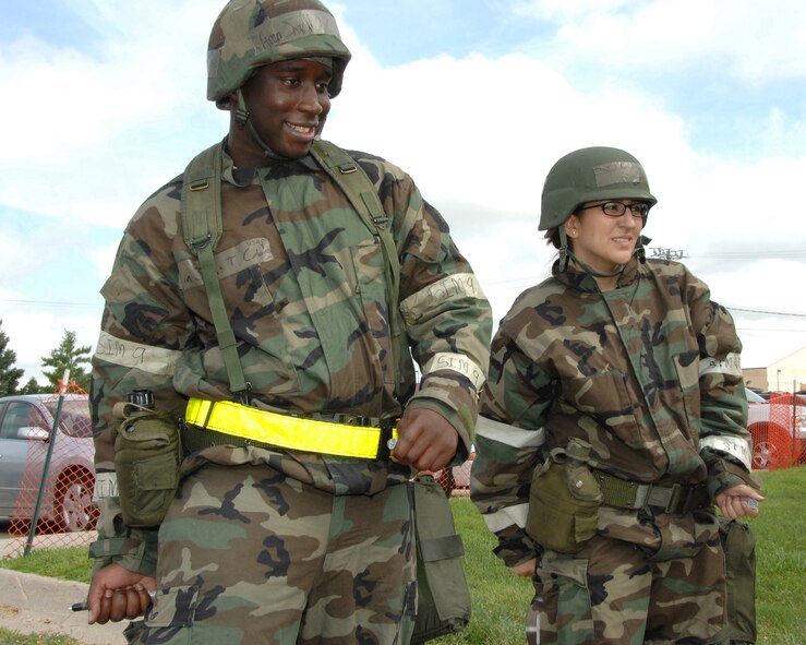 OFFUTT AIR FORCE BASE, Neb. -- Airman 1st Class Jarvis Cobb, left and Staff Sgt. Yaneth Tebo, right, both with the 55th Force Support Squadron, simulate injecting themselves with nerve agent antidote during combat day here July 14. U..S. Air Force Photo by Dana Heard