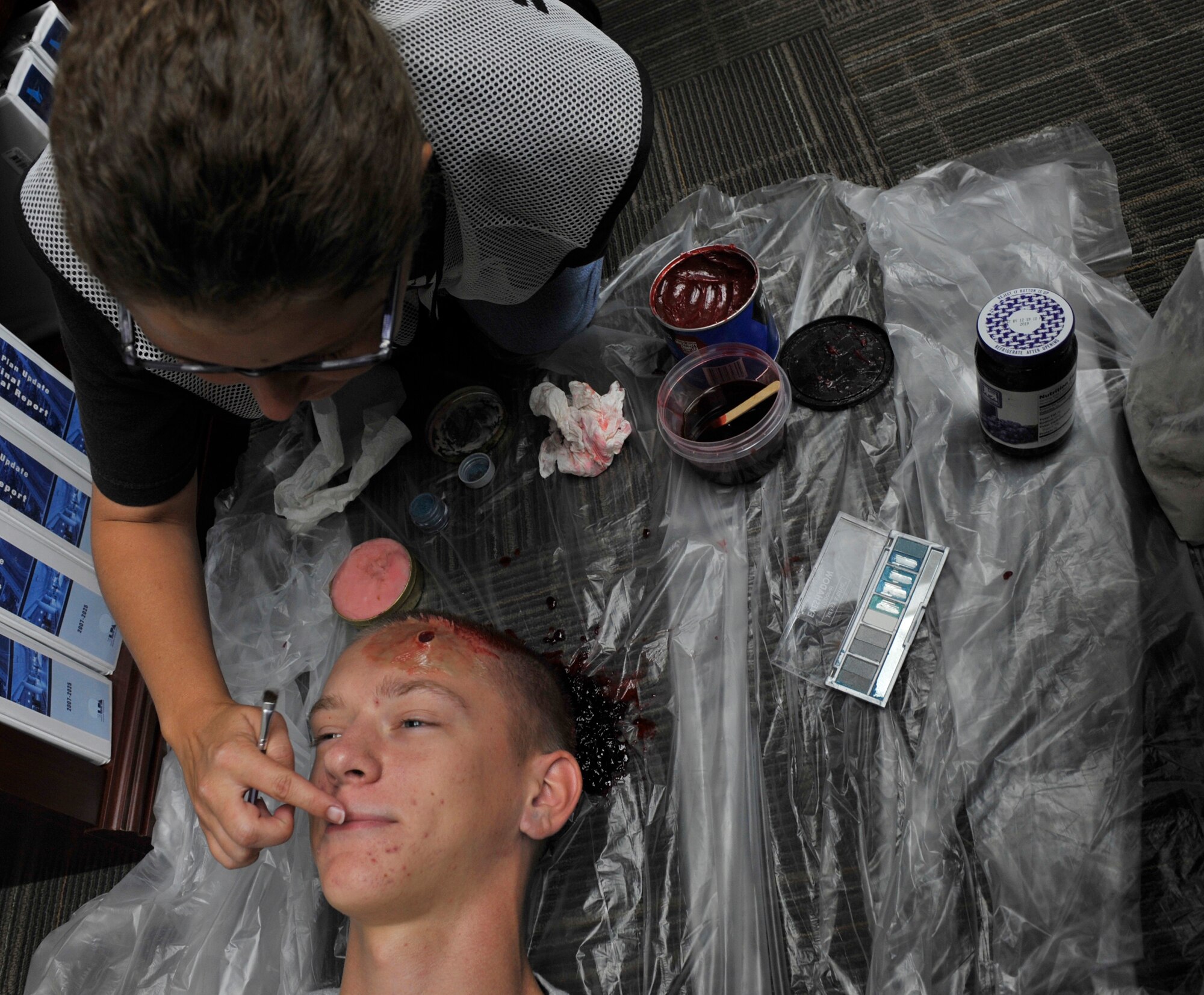 MOODY AIR FORCE BASE, Ga. -- Jennifer Barnes, moulage officer, applies makeup on Airman 1st Class Ryan Hill, 23rd Communications Squadron radar maintenance, at the Valdosta Regional Airport July 18. Airman Hill role played a hostage victim during a hostage exercise to test local mutal aid procedures. (U.S. Air Force photo by Senior Airman Schelli Jones)