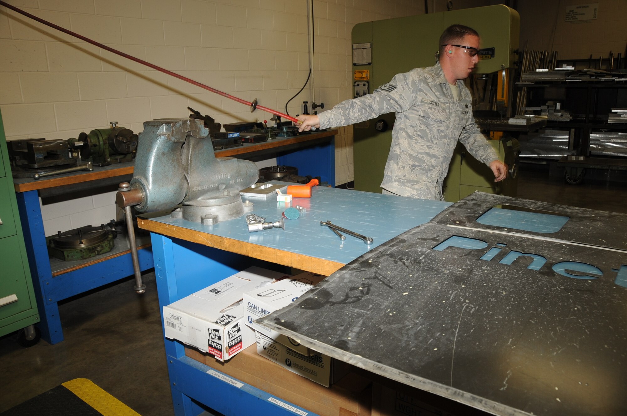 Staff Sgt. Brandon Cotter, 28th Maintenance Squadron metals technician journeyman, pulls an air compressor hose before attaching a sanding disk to it here, July 16.  Sergeant Cotter sanded two pieces of a hydraulic support block to ensure they were completely smooth before fitting them together. (U.S. Air Force photo/Senior Airman Anthony Sanchelli)