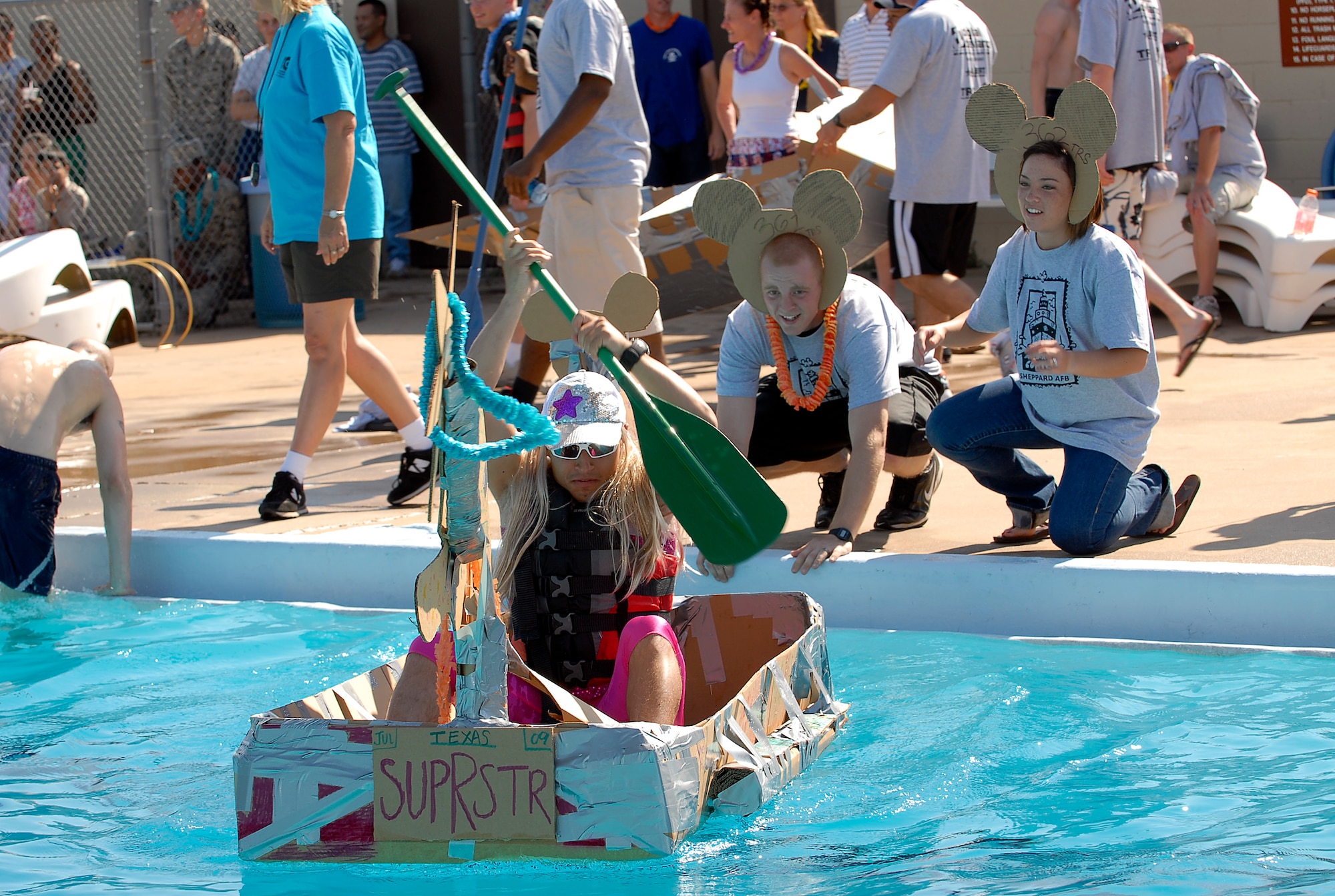 Airman Luiz Azevedo, a student from the 362d Training Squadron, gets a push off at the start of the Build-a-Boat-Race July 18, by his teammates. The team won the overall Commander’s Choice and the Jewel of the Pool awards in the race. (U.S. Air Force photo/Harry Tonemah)