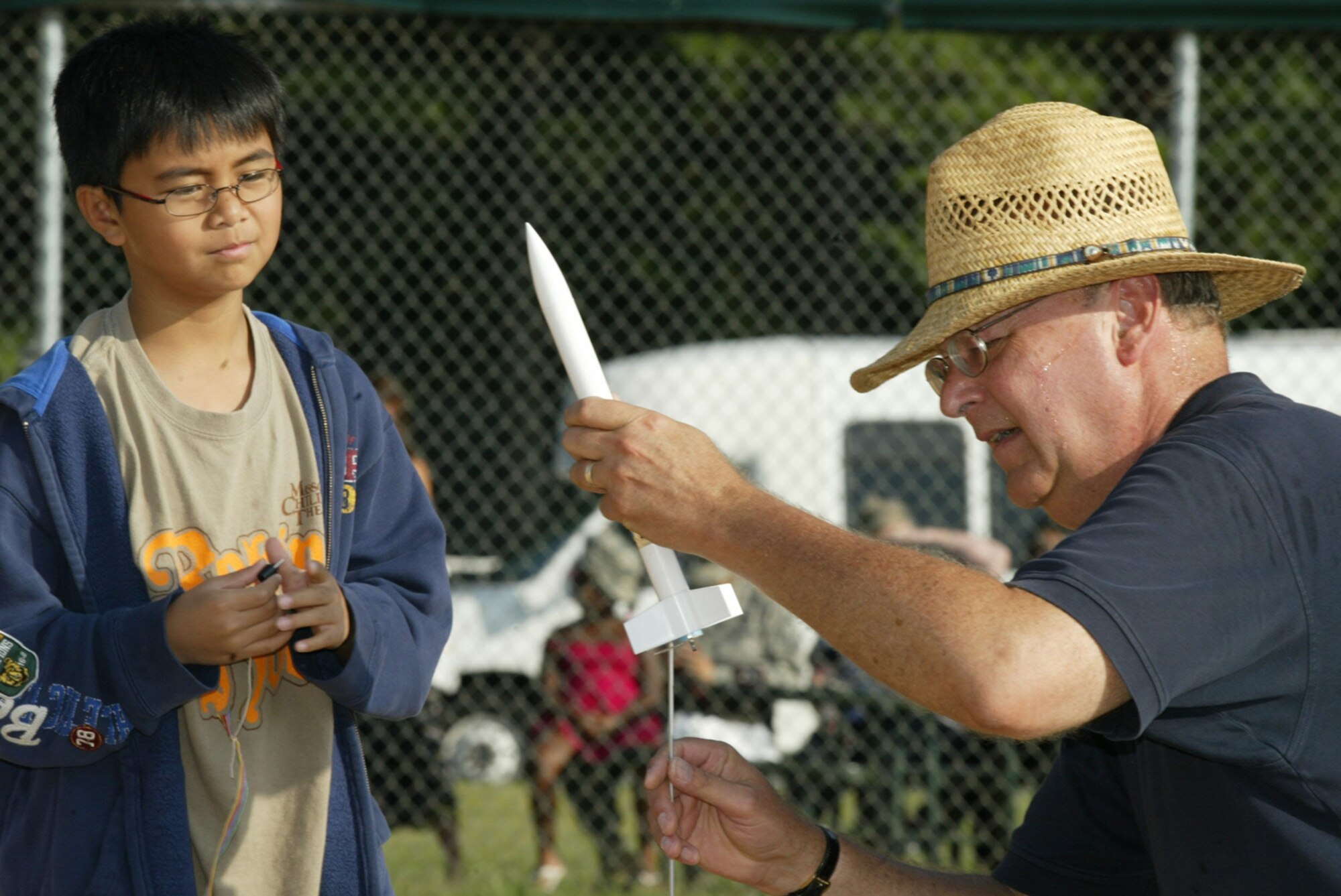 Chief Master Sgt. (ret.) Jim Jackson, STARBASE instructor, assists Alonzo "Wolfe" Dinogan with a rocket he assembled as a STARBASE project prior to its launch at the Dobbins Lakeside softball field July 16. The four-day program taught children of DoD members about science, math, technology and aviation. (U.S. Air Force photo/Don Peek)