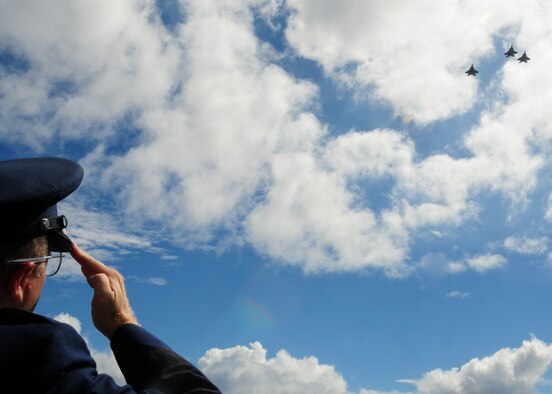 ANDERSEN AIR FORCE BASE, Guam - Brig. Gen. Phil Ruhlman, 36th Wing commander, salutes as an F-22 missing man formation flies over a memorial unveiling service held at the Governor's Complex at Adelup Point in Hagatna, Guam, July 20. The Raider 21 memorial was designed as a tribute to the six men who lost their lives a year ago and is dedicated to demonstrate that our fallen brothers our fallen brothers are not forgotten.(U.S. Air Force photo/Senior Airman Nichelle Anderson) 