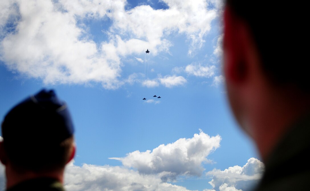 ANDERSEN AIR FORCE BASE, Guam - Airmen from the 20th Expeditionary Bomb Squadron stand at attention while a F-22 Raptors perform a missing man formation above during a memorial ceremony at the Governor's Complex at Adelup Point in Hagatna, Guam, July 20. Family, friends and co-workers of Raider 21 along with Team Andersen and Guam community members honored the memory of the Raider 21 aircrew with a ceremony and an unveiling of a memorial dedicated to the Airmen. (U.S. Air Force photo by Airman 1st Class Courtney Witt)





