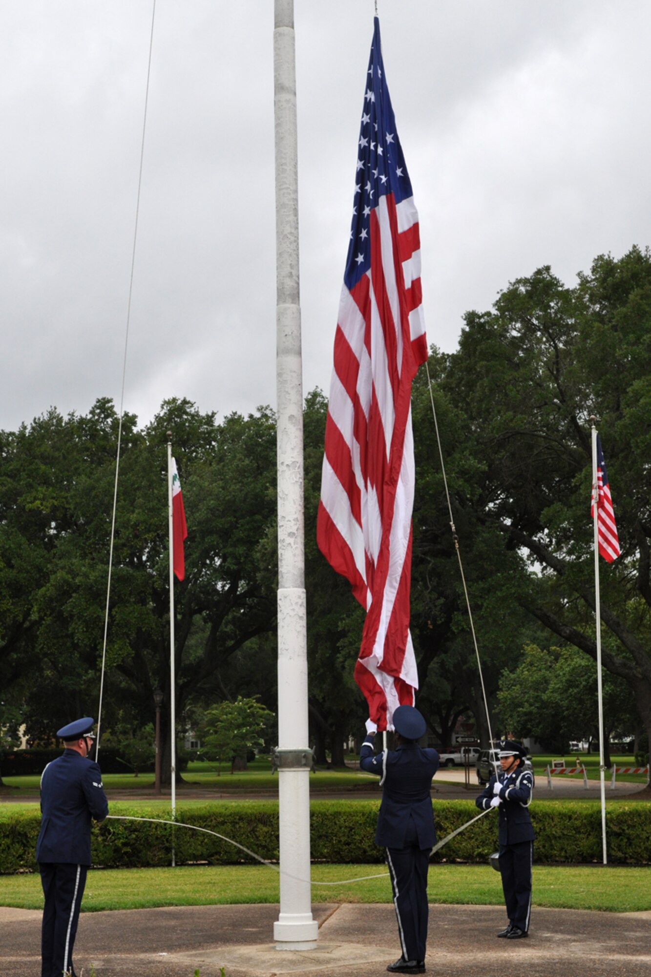 Members of the Barksdale Air Force Base Honor Guard place the flag at half mast to begin the RAIDR 21 Remembrance Ceremony in front of the 2nd Bomb Wing Headquarters building at Barksdale AFB, La., July 21, 2009. Family, friends and more than 200 Airmen were in attendance at the ceremony that remembered the six aircrew members who were lost a year ago off the coast of Guam. (U.S. Air Force photo/Tech. Sgt. Jeff Walston)