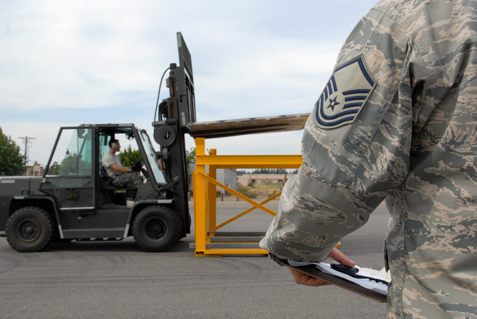 MCCHORD AIR FORCE BASE, Wash. – An Air Mobility Command aerial porter umpire watches Staff Sgt. Clifton Robertson, 735th Air Mobility Squadron, Hickam Air Force Base, Hawaii, navigate a serpentine driving course in a 10,000-ton forklift during the Air Mobility Rodeo 2009 here. Sergeant Robertson is part of the 515th Air Mobility Operatons Wing team from Hickam AFB, which will compete against 22 other aerial port teams. Events include C-130 engine running on and off load, joint inspection with hazmat, in-transit visibility, 60,000-ton driving course, and a 10,000-ton forklift driving course. (U.S. Air Force photo/Staff Sgt. Carolyn Viss)