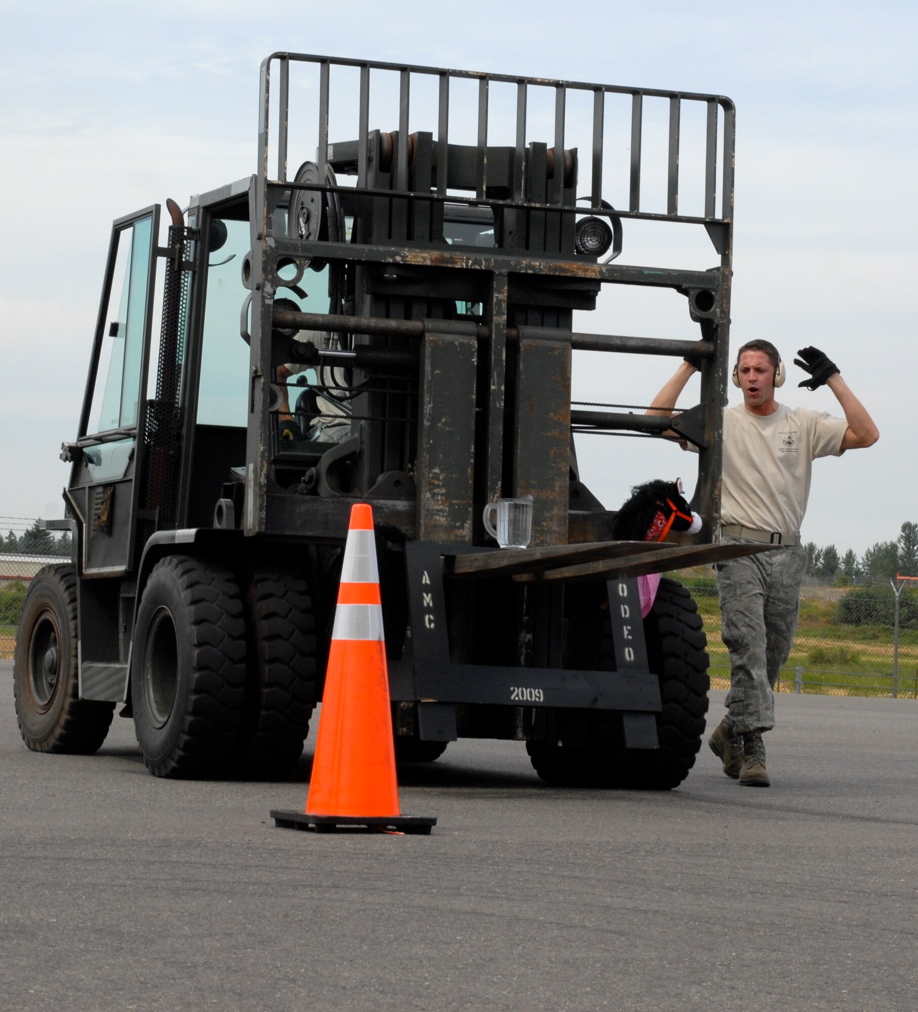 MCCHORD AIR FORCE BASE, Wash. – Staff Sgt. Clifton Robertson, 735th Air Mobility Squadron, Hickam Air Force Base, Hawaii, directs Senior Airman Andrew Cramer, 732th Air Mobility Squadron, Elmendorf Air Force Base, Alaska, as he drives a 10,000-ton forklift through a serpentine course on the flightline in front of an inspector during the Air Mobility Rodeo 2009 here July 20. On the front of the forklift is a “horse” carrying a pitcher full of water, which Airman Cramer had to avoid spilling during the event. Both Airmen are part of the 515th Air Mobility Operatons Wing team from Hickam AFB, which will compete against 22 other aerial port teams. Events include C-130 engine running on and off load, joint inspection with hazmat, in-transit visibility, 60,000-ton driving course, and a 10,000-ton forklift driving course. (U.S. Air Force photo/Staff Sgt. Carolyn Viss)