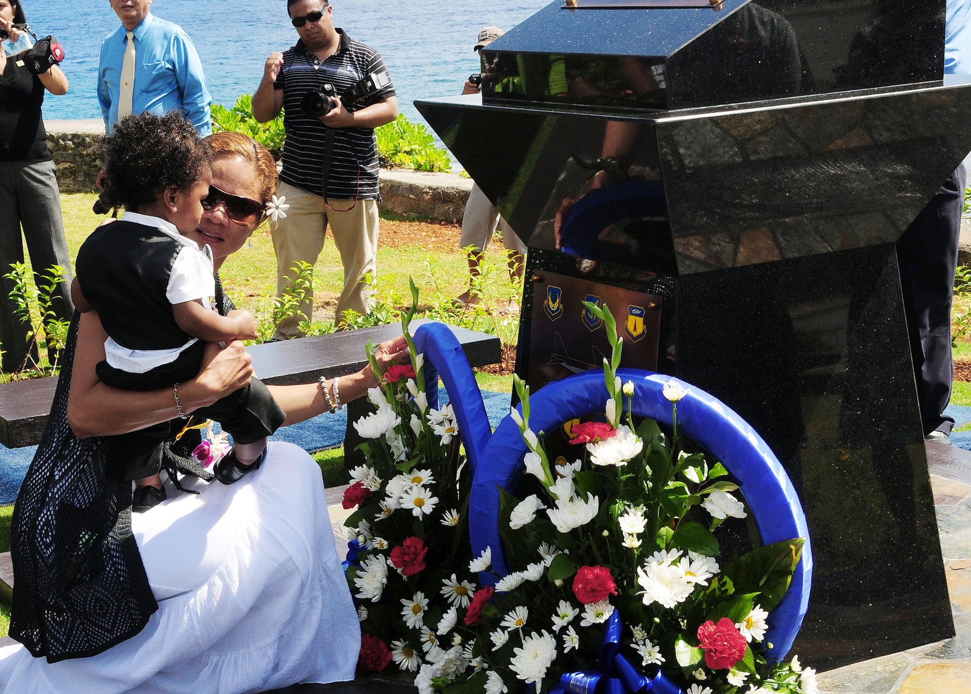 Ursula Martin, wife of Col. George Martin, and their son Guahan Martin lay a wreath at the base of the RAIDR 21 Monument at the Governor's Complex at Adelup Point in Hagatna, Guam, July 20.  They placed the wreath in remembrance of the husband and father they lost July 21, 2008, when a B-52 Stratofortress -- call sign RAIDR 21 -- crashed off the coast of Guam during a mission.  Colonel Martin was one of six crewmembers who perished.  More than 300 family, friends and guests attended the ceremony and monument unveiling.  (U.S. Air Force photo/Senior Airman Nichelle Anderson)