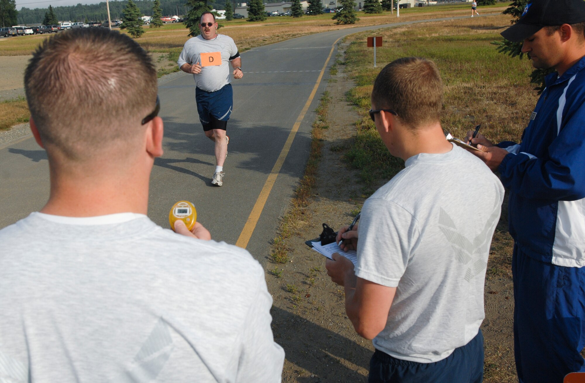 ELMENDORF AIR FORCE BASE, Alaska -- PT test evaluators watch a runner pass the finish line during a testing session July 17. In a joint effort to test all of Elmendorf's Airmen, The Health and Wellness Center has teamed up with physical training leader volunteers from around base to assist with the centralized PT testing. (U.S. Air Force photo/Senior Airman David Carbajal)