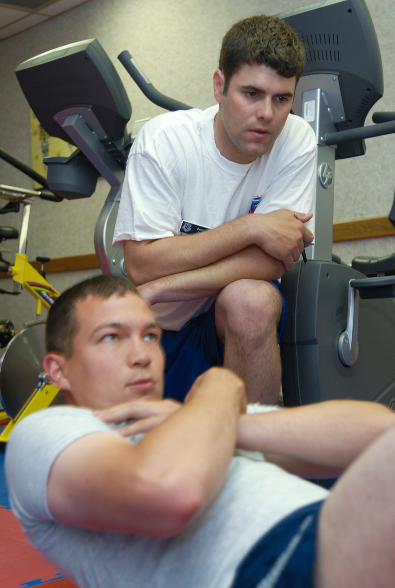 ELMENDORF AIR FORCE BASE, Alaska -- Patrick Lais observes the sit ups of Staff Sgt. Christopher Larsen during a testing session July 17. The Health and Wellness Center have begun employing civilian and contracted members to take over the centralized PT testing. Lais is a fitness test cell specialist with the HAWC. Larsen is a member of the 3rd Maintenance Group. (U.S. Air Force photo/Senior Airman David Carbajal)