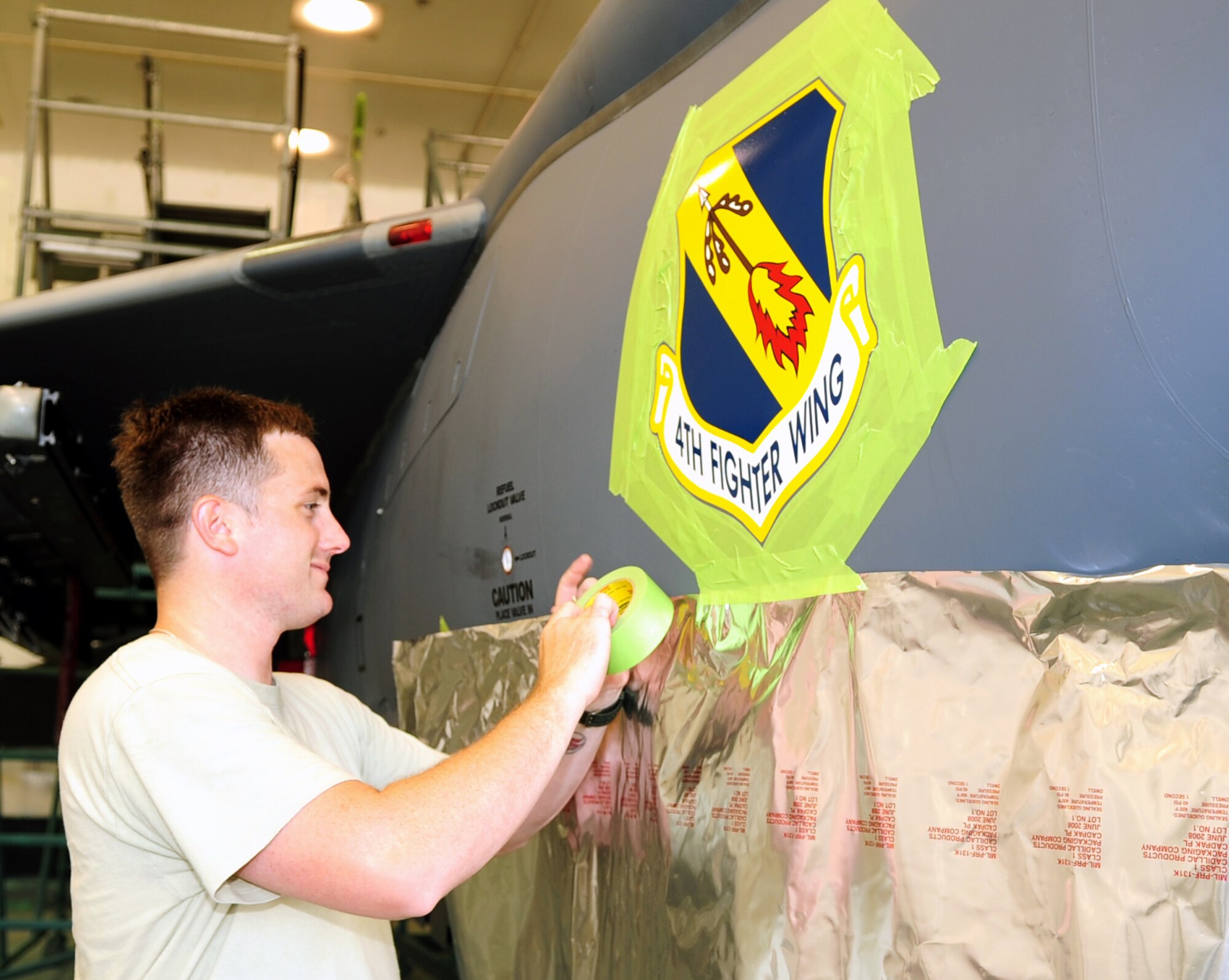 Senior Airman Jonathon Shanley, 4th Equipment Maintenance Squadron aircraft structural maintenance journeyman, masks off the 4th Fighter Wing patch on an F-15E Strike Eagle at Seymour Johnson Air Force Base, N.C., July 14, 2009. The paint barn is where jets are taken for new coats of paint and squadron and wing designators. (U.S. Air Force photo by Airman 1st Class Rae Perry)