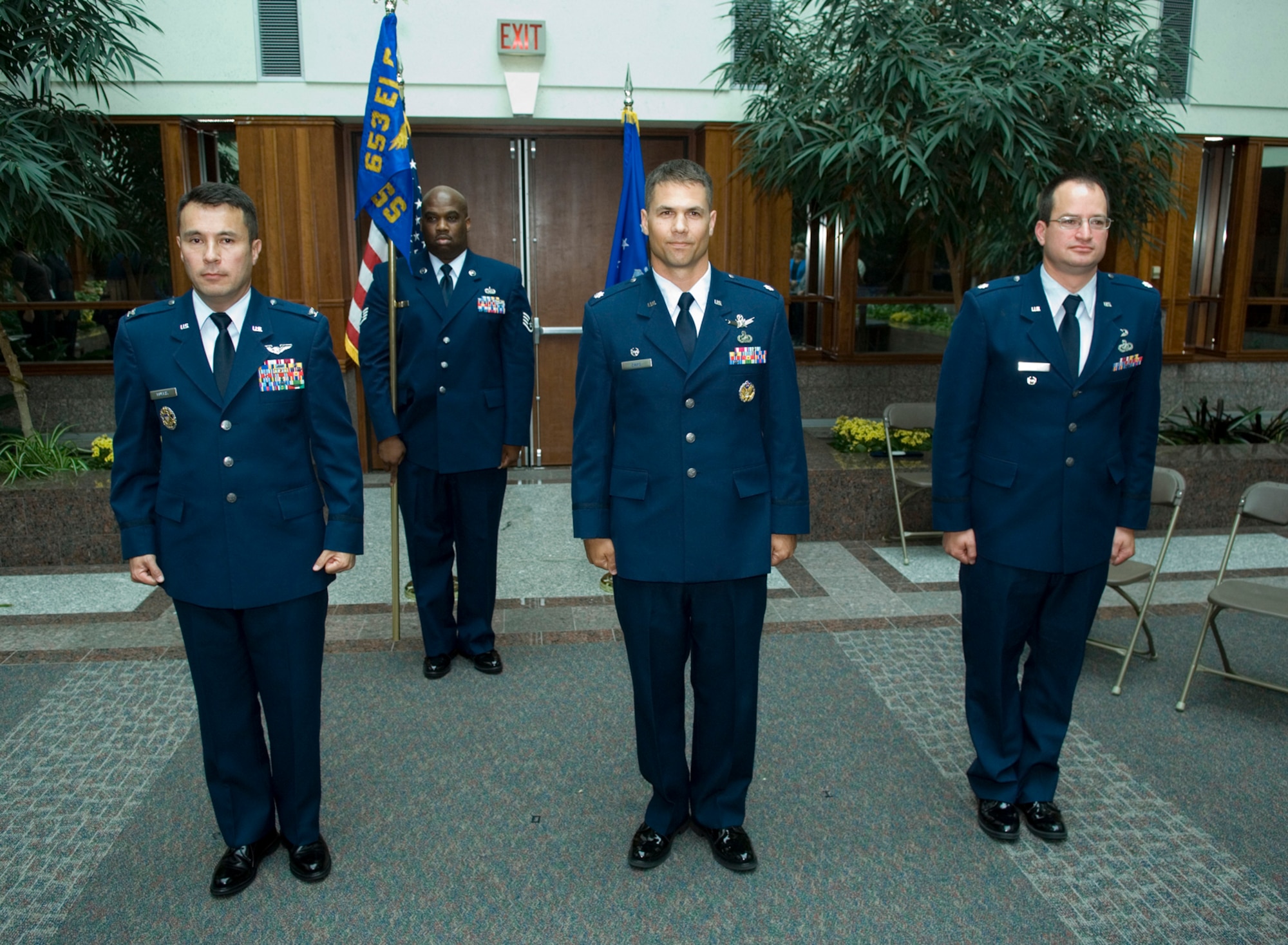 653rd Electronic Systems Wing Vice Director Col. Mark Murphy (foreground, from left) stands at attention with new 639th Electronic Systems Squadron Commander Lt. Col. Mark Davis and outgoing 639th Electronic Systems Squadron Commander Lt. Bryan Bagley during the change of command ceremony held in the Mitre building July 8. Colonel Murphy officiated and Staff Sgt. Damion Daniels (background), 653rd Electronic Systems Group, served as the guidon bearer as Colonel Davis assumed command of the squadron.  (U.S. Air Force photo by Rick Berry)