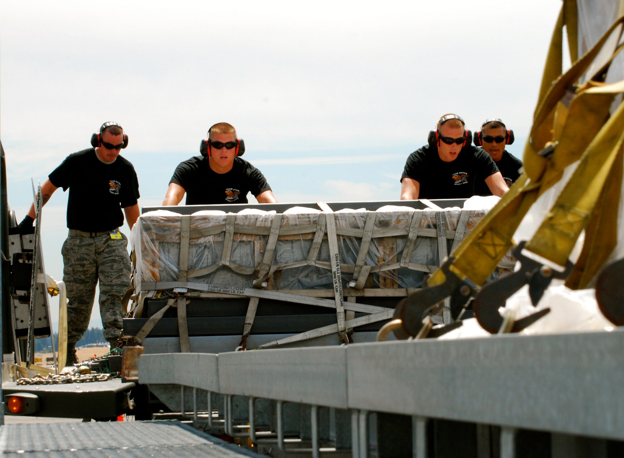 Team Dover port dawgs work together to push a pallet off a 60K loader during a graded exercise July 20. Aerial Porters from the 512th and 436th Airlift Wings team up at the Air Mobility RODEO at McChord Air Force Base, Wash., where their skills are tested on events aimed at moving cargo and passengers. More than 100 teams are participating in RODEO, including teams from seven foreign countries. The international combat skills and flying operations competition is designed to develop and improve techniques, procedures and enhance mobility operations. (U.S. Air Force photo/Staff Sgt. Steve Lewis)