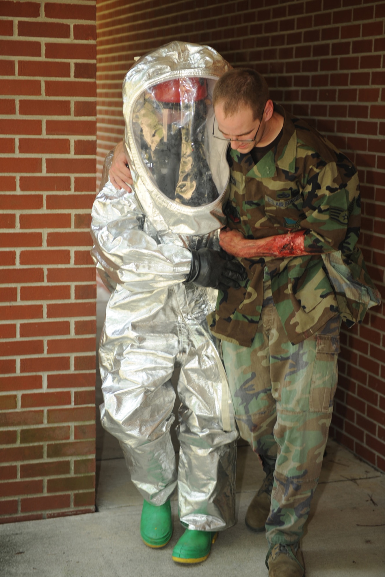 Airman 1st Class Dustin Beckley, 4th Civil Engineer Squadron firefighter, assists Airman 1st Class Jesse Bennett, 4th Equipment Maintenance Squadron, during an all hazard response training exercise here at Seymour Johnson AFB, N.C., July 15, 2009. The purpose of the exercise was to prepare Airmen for chemical, biological, radiological and nuclear emergencies. (U.S. Air Force photo by Senior Airman Ciara Wymbs) 