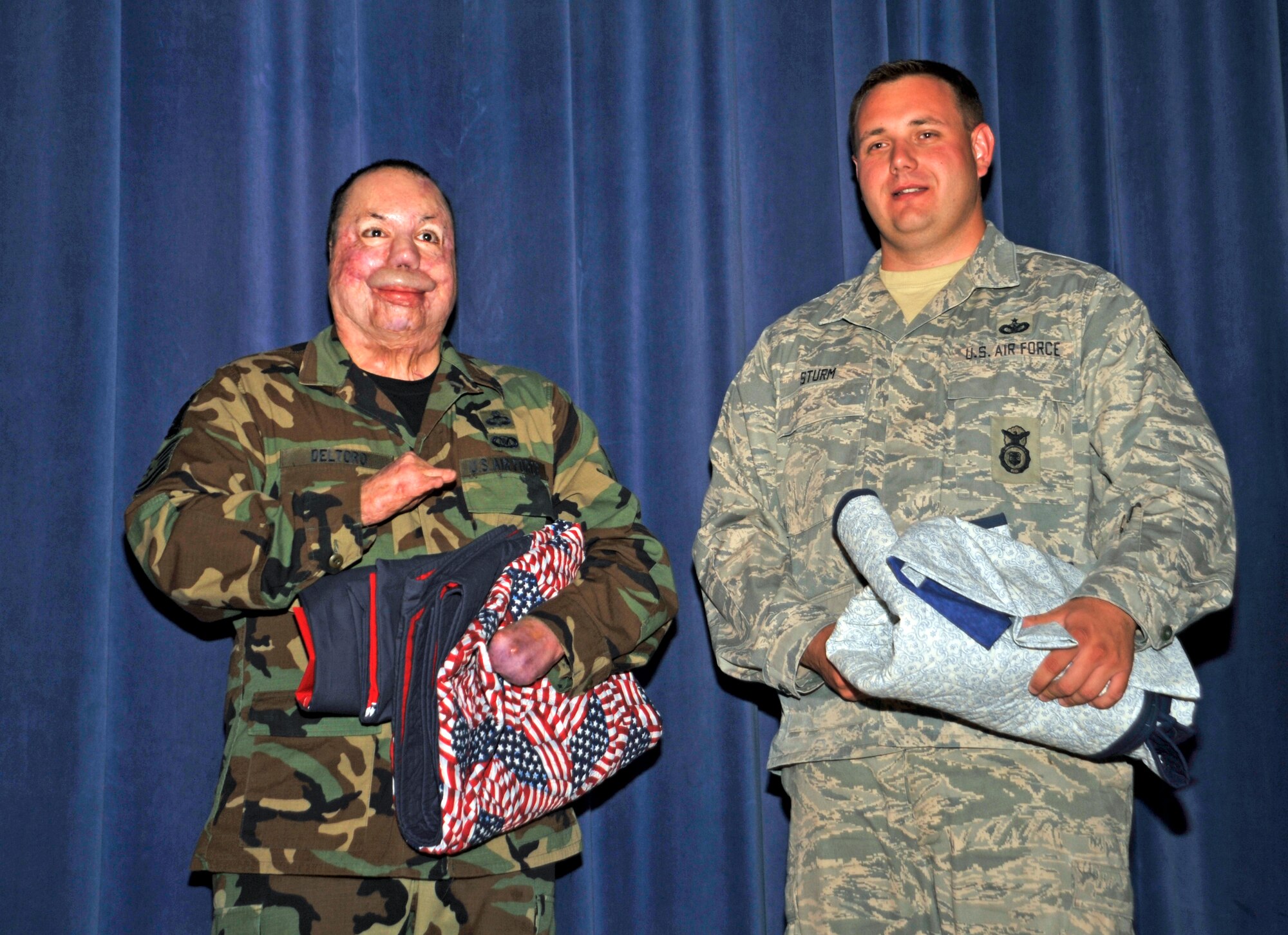 Joint terminal attack controller Tech. Sgt. Israel Del Toro (left) and Staff Sgt. Rory Sturm, 721st Security Forces Squadron, hold gifts presented to them by a local representative of the Noncommissioned Officers Association, after the Wounded Warrior Panel held in the base auditorium July 17. Both NCOs discussed their battlefield experiences with an audience of approximately 500 Airmen.  (Air Force photo by Roberta McDonald) 