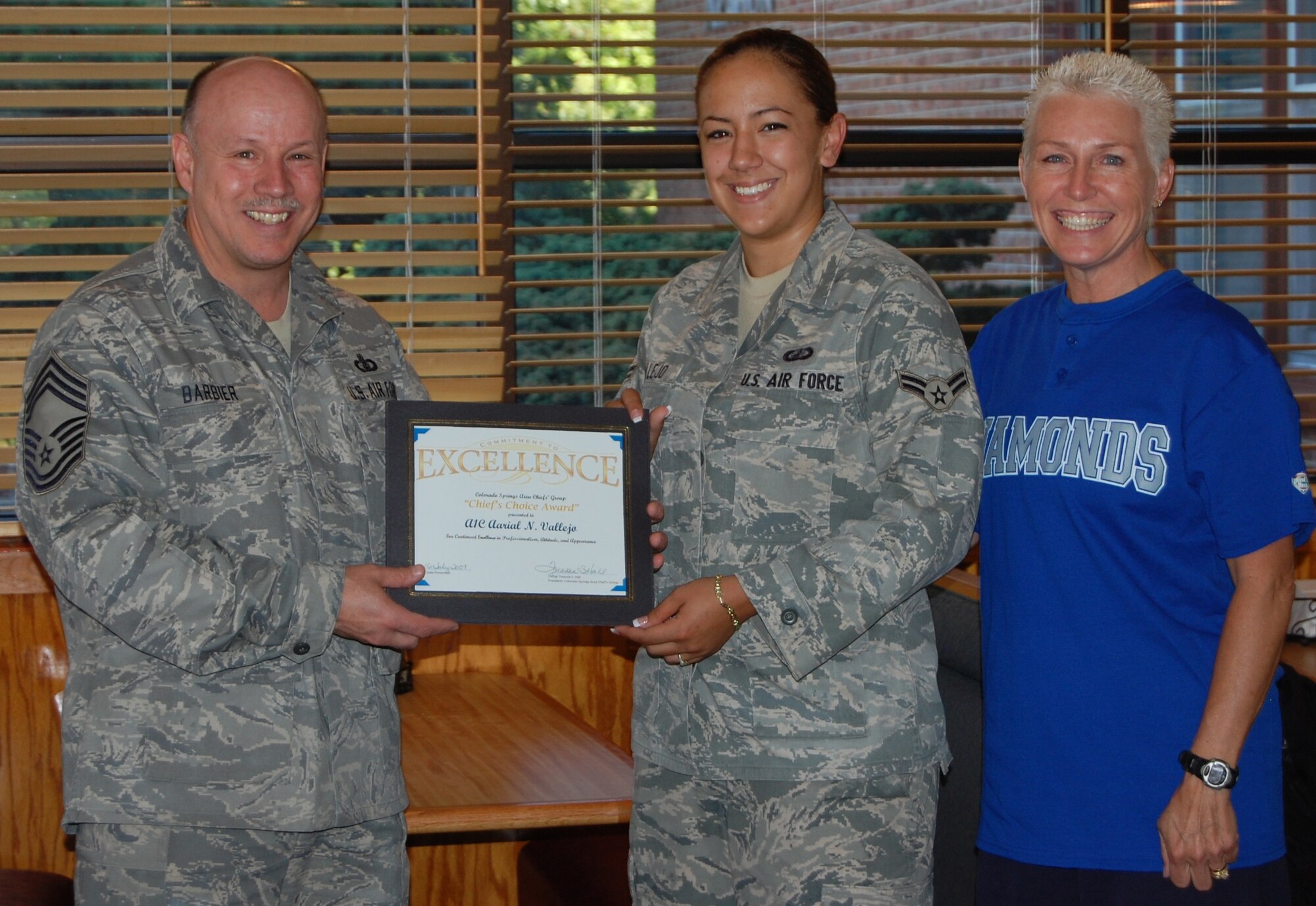 Chief Master Sgt. Scott Barbier (left), USAF Academy Band, and Chief Master Sgt. Treassia Hall (right), president of the Chief’s Group, presented Airman 1st Class Aarial Vallejo, 21st Comptroller Squadron, the Chief’s Choice Award for her customer service and professionalism. (U.S. Air Force photo)