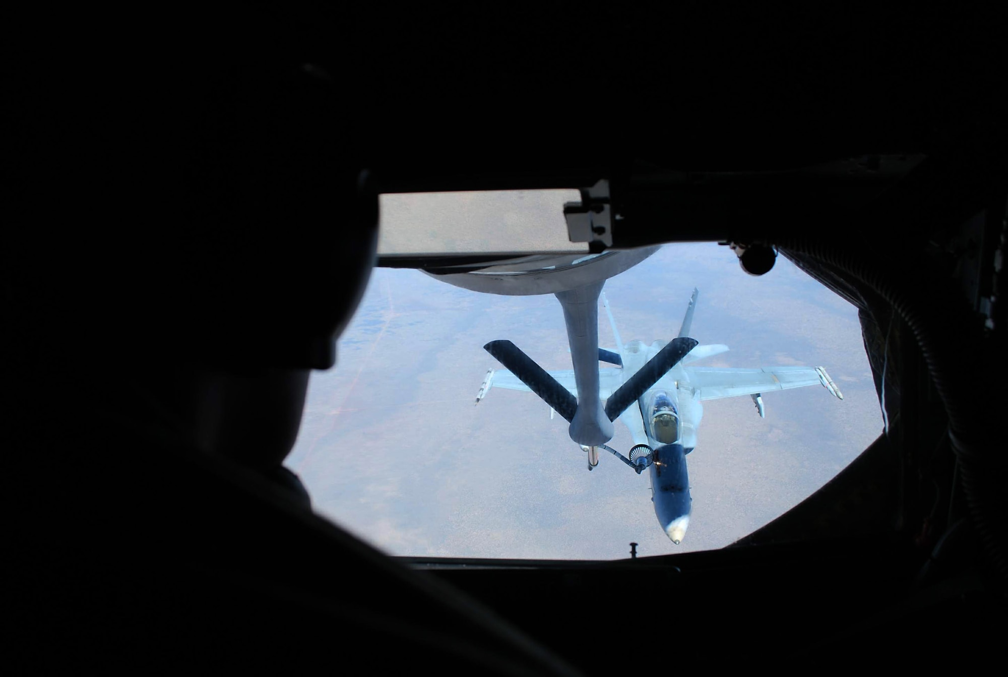 Beyond the silhouette of Staff Sgt. Kenneth Harwood, a Royal Australian Air Force F-18 receives fuel July 19 over Australia. The aircraft were participating in a mock air war over Australia as part of Exercise Talisman Saber 2009. Sergeant Harwood is 909th Air Refueling Squadron instructor boom operator from Kadena Air Base, Japan. (U.S. Air Force photo/Capt. Bryan Lewis)