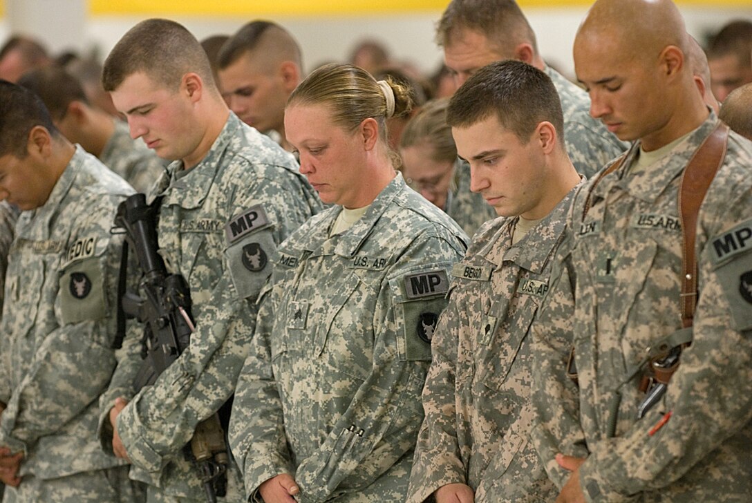 U.S. Army soldiers bow their heads in prayer during a memorial service honoring three fallen comrades who were killed in action as the result of a rocket attack on Contingency Operating Base Basra, Iraq, July 20, 2009.