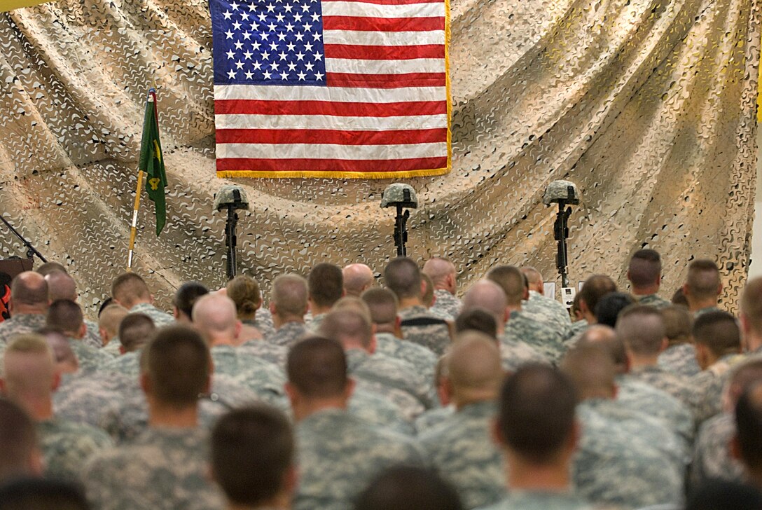 U.S. Army soldiers attend a July 20, 2009, memorial service honoring three fallen comrades who were killed in action as the result of a rocket attack on Contingency Operating Base Basra, Iraq, July 16, 2009.