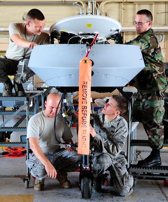 HOLLOMAN AIR FORCE BASE, N.M. -- (Clockwise from top left) Staff Sgt. Jake Gauvin, Staff Sgt. Jason Hutchinson, Senior Airman Joseph Bistline and Staff Sgt. Jeremy Crombie of the 432nd Wing prepare an MQ-1B Predator to receive it's sensor pod July 20. (U.S.Air Force photo by Tech. Sgt. Chris Flahive) (Released)