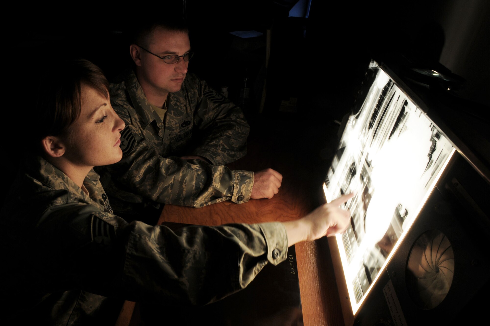 Staff Sgt. Cortney Coker looks over an X-ray image of a section of F-15E Strike Eagle with Tech. Sgt. Sterling Rosenau July 17 at Royal Air Force Lakenheath, England. X-rays of the aircraft are taken before and after inspections and then compared for variations or defects. Sergeant Coker is a 48th Equipment Maintenance Squadron nondestruction inspection journeyman, and Sergeant Rosenau is a 48th EMXS F-15E crew chief. (U.S. Air Force photo/Staff Sgt. Nathan Gallahan) 