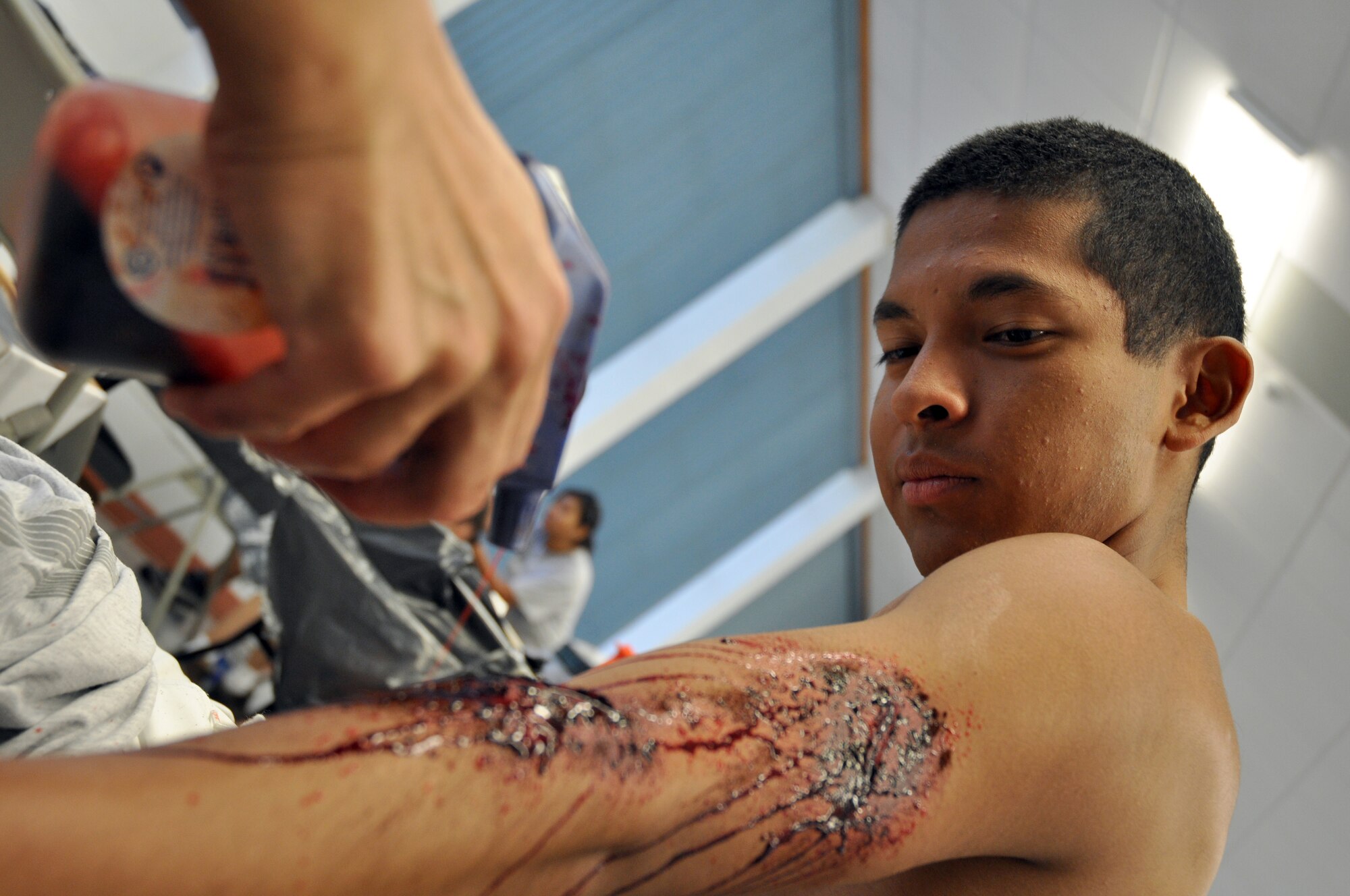 EGLIN AIR FORCE BASE, Fla. – Airman 1st Class Jose DeJesus, Explosive Ordinance Disposal 366th Training Squadron, watches as moulage is applied for an exercise at the West Gate Chapel July 22. Moulaging victims for exercise scenarios enable medical personnel to better train for real-world possible situations when they deploy. (U.S. Air Force photo/ Airman Anthony Jennings)