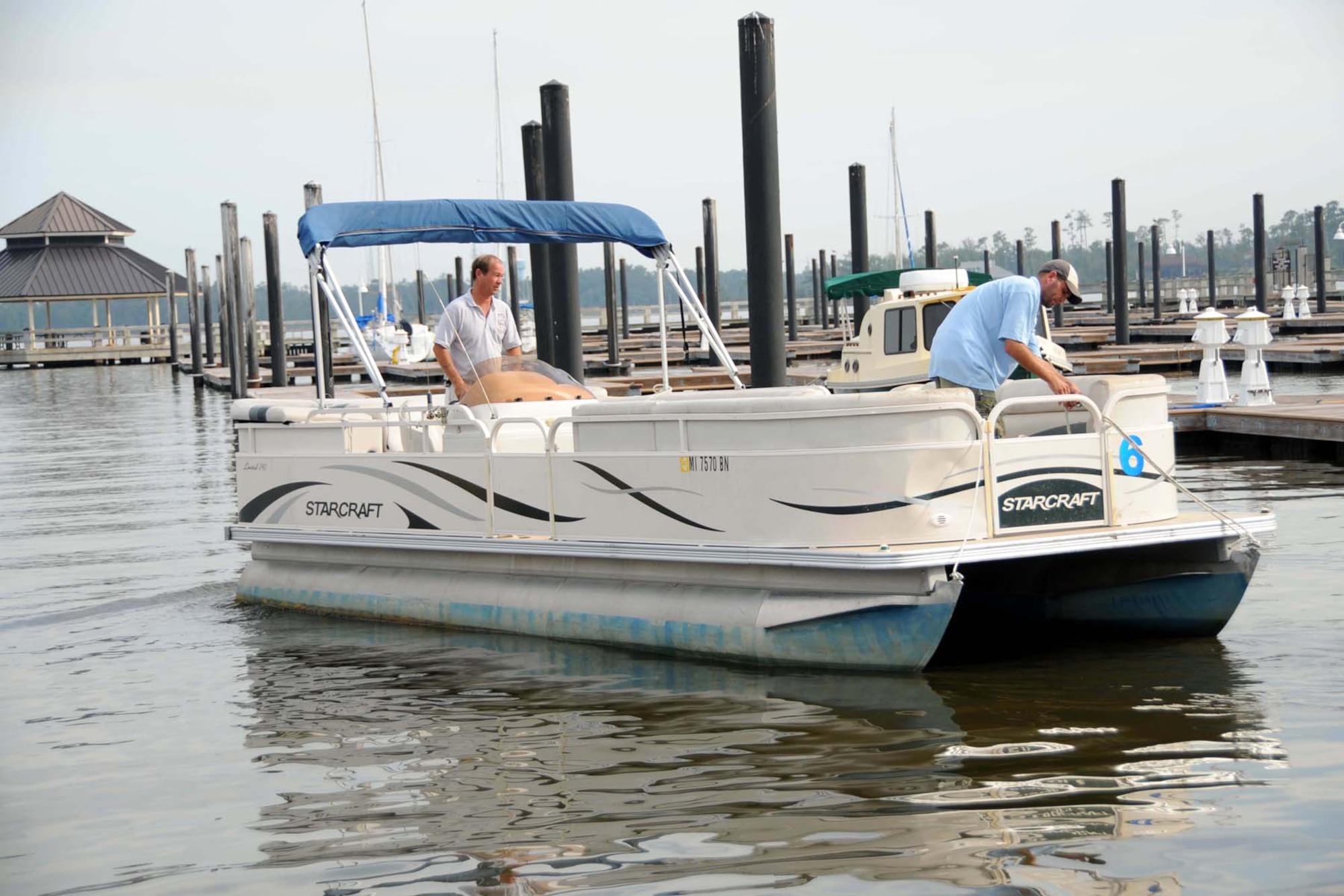 Outdoor recreation employees Wayne Fortier, left, and Joe Heflin return a pontoon boat to the dock.  Free certification training is provided to people who want to rent a pontoon boat.  (U.S. Air Force photo by Kemberly Groue)