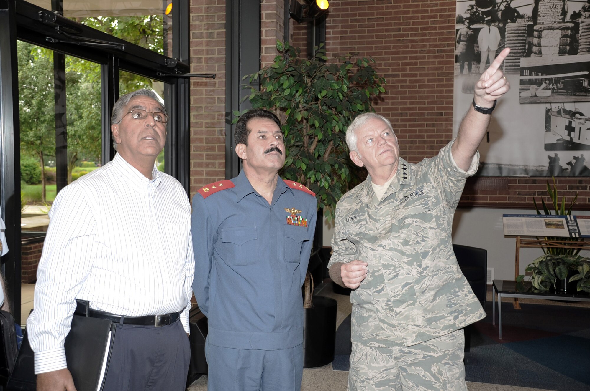 Upon entering the Air Mobility Command headquarters building at Scott Air Force Base, Ill., Gen. Arthur J. Lichte, AMC commander, points out a piece of air mobility history to Maj. Gen. Mohammad Dawran, commander of the Afghan National Army Air Corps, and M. Monir Rafiq, Department of Defense interpreter, during the Afghan delegation's visit here July 15.  General Dawran's was visiting to continue an open dialog between senior military leaders of the two countries and to reinforce airlift concepts that are being applied throughout Afghanistan. U.S. (Air Force photo/Mark Diamond) 