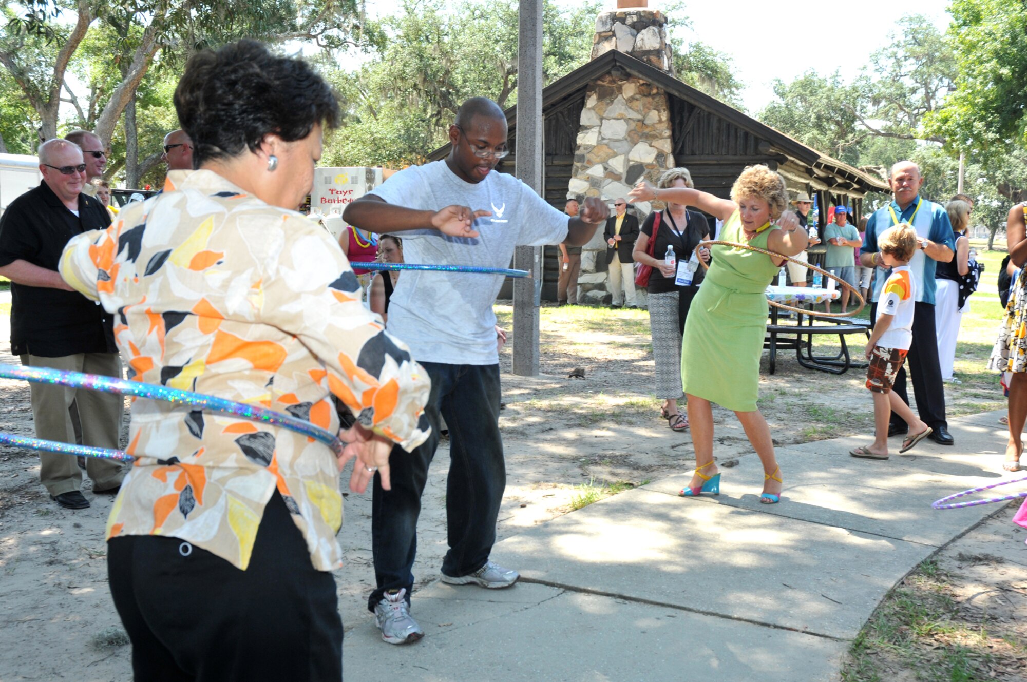 From left, Diane Patrick, wife of Massachusetts Gov. Deval Patrick; Airman Basic Justin Peoples, 334th Train-ing Squadron, and Gayle Manchin, wife of West Virginia Gov. Joe Manchin, demonstrate their hula-hoop skills at Saturday’s luau at marina park.  The event was organized to entertain and honor families of Keesler’s deployed members.  (U.S. Air Force photo by Adam Bond)