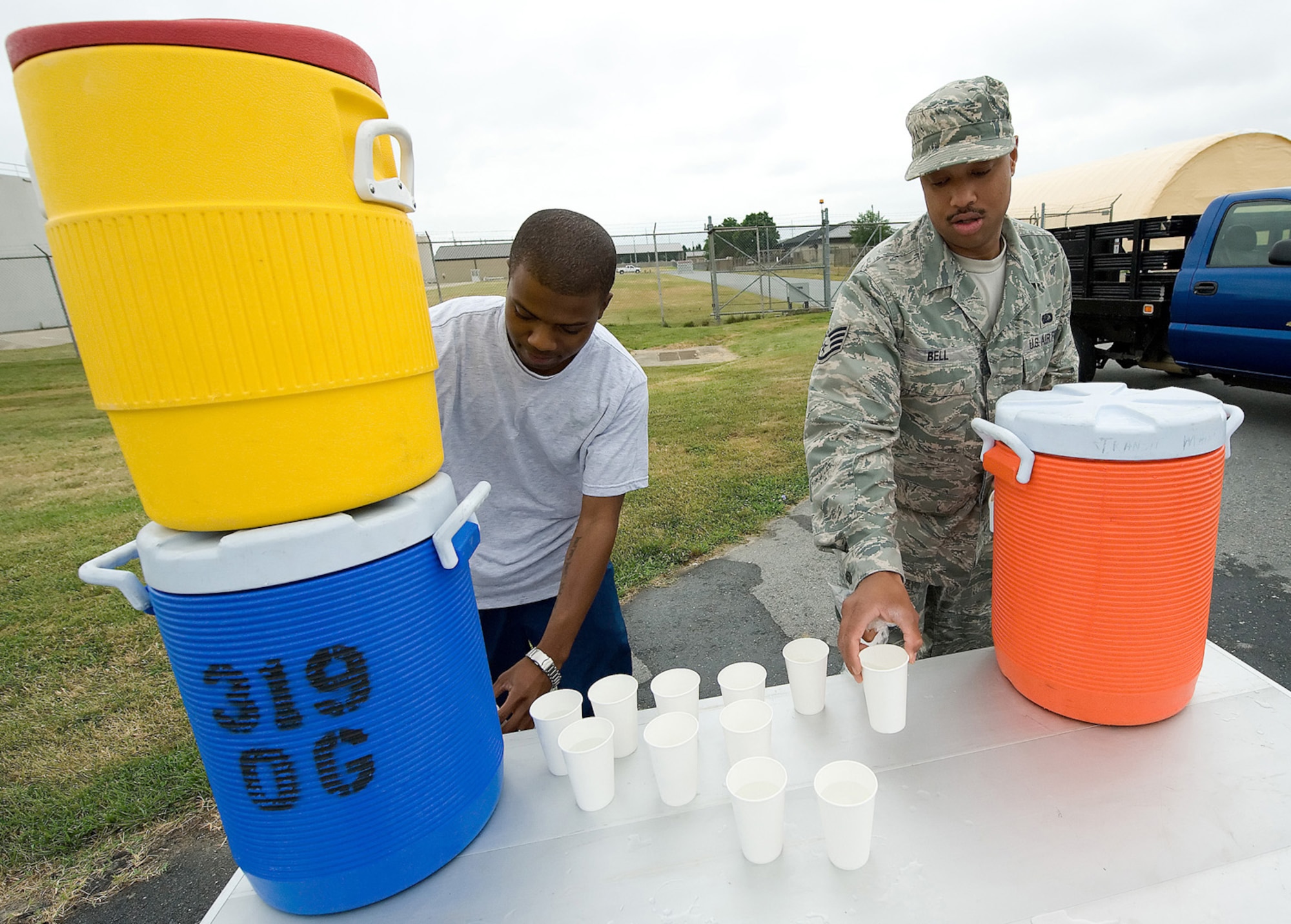 (Left to right) Senior Airman Zachary Walker, 436th Communications Squadron, and Staff Sgt. Charles Bell, Air Force Mortuary Affairs Operations Center mortuary specialist, volunteer handing out water for the warrior run July 21 at Dover Air Force Base, Del. (U.S. Air Force photo/Jason Minto)