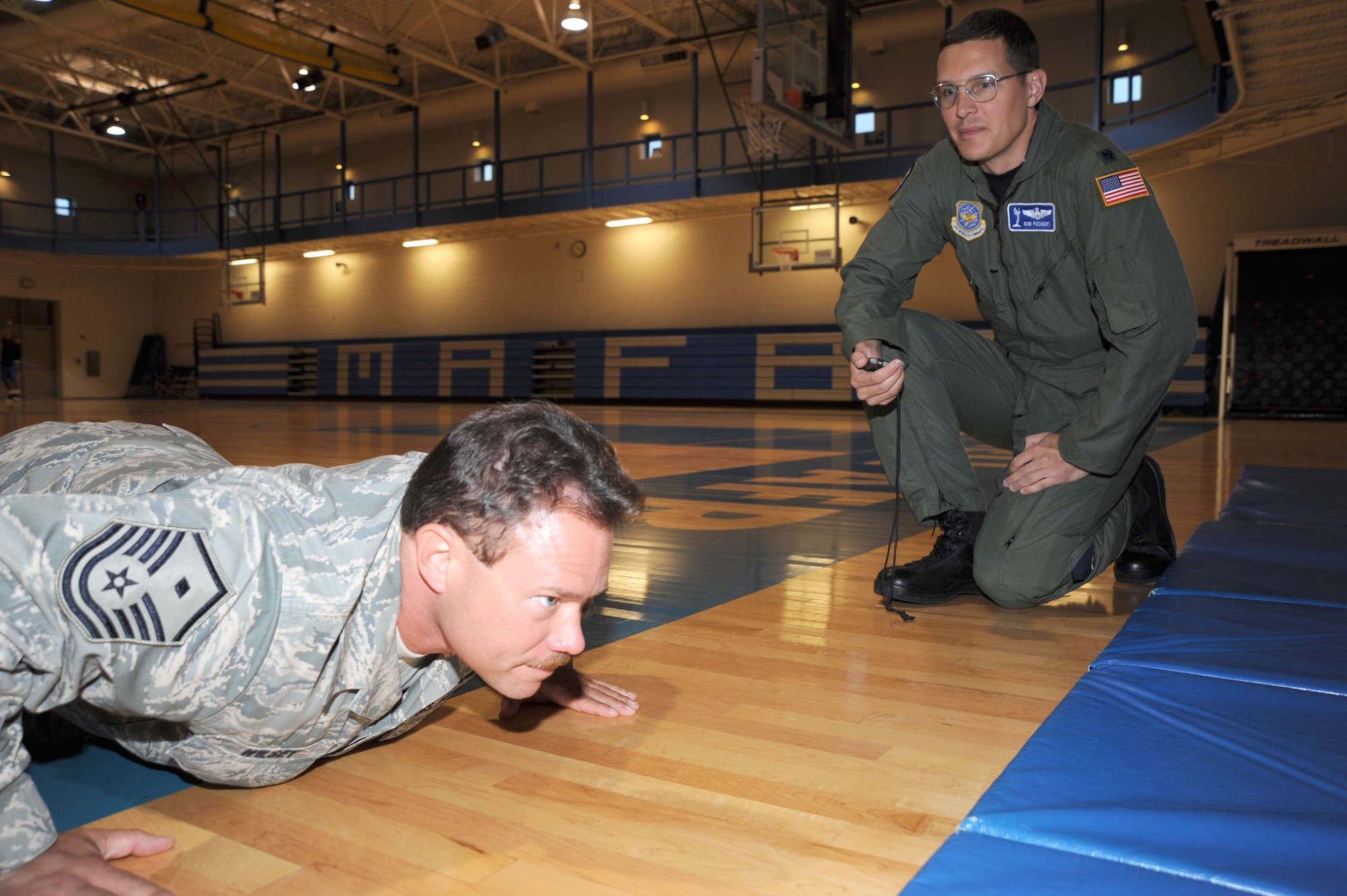 MCCONNELL AIR FORCE BASE, Kan. -- Lt. Col. Robert Pochert, 344th Air Refueling Squadron, watches Master Sgt. Michael Wilsey, 22nd Civil Engineer Squadron first sergeant, as he participates in the push-up contest held at the base gymnasium, July 15. Team McConnell members pledged money in the contest as a fundraiser for the Rodeo team. (Photo by Technical Sgt. Chyrece Campbell)