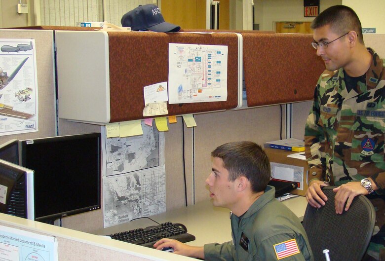 (Left) Cadet First Class Bryan Holtz works on designing a database as 1st Lt. Douglas Wilson of the Air Force Operational Test and Evaluation Center’s Detachment 5 at Edwards Air Force Base, Calif., observes his progress. Cadet Holtz participated with 12 other U.S. Air Force Academy cadets in the USAFA Cadet Summer Research Program at different AFOTEC locations. Cadets worked on a variety of real-world Air Force projects ranging from the F-22 to the Miniature Air Launched Decoy for five weeks. (U.S. Air Force photo).