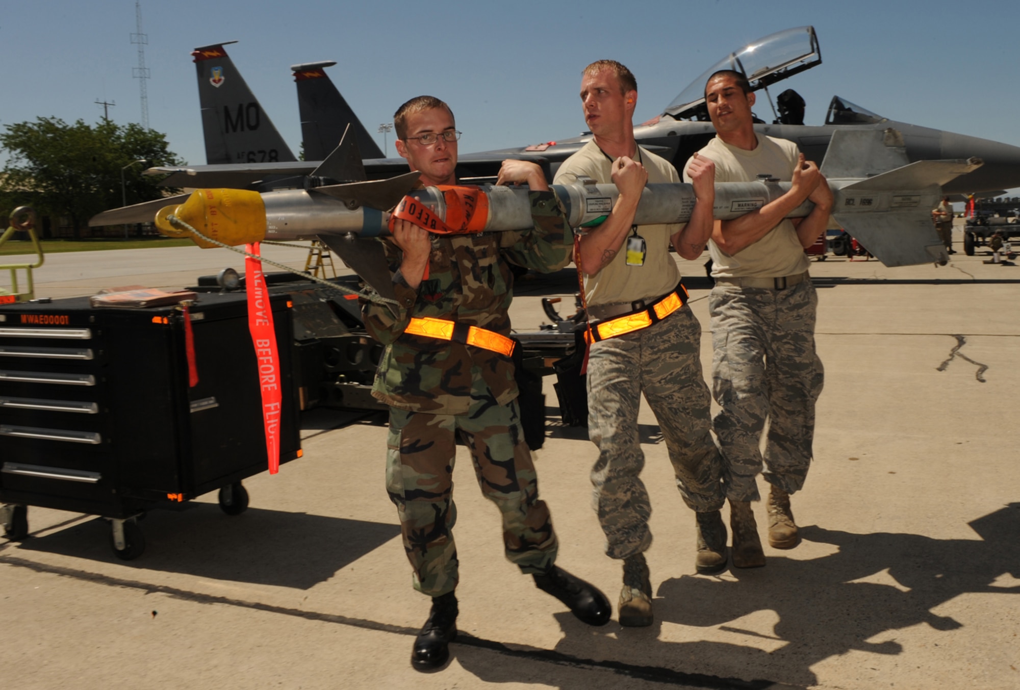 MOUNTAIN HOME AIR FORCE BASE, Idaho-- Left, Senior Airman Robert Pennock, Staff Sgt. David Foster and Senior Airman Phillip Koehn, all 391st Aircraft Maintenance Unit weapons load technicians, race against the clock during the a weapons load crew competition July 10. The 390th AMU took first place. (U.S. Air Force photo by Airman 1st Class Renishia Richardson)