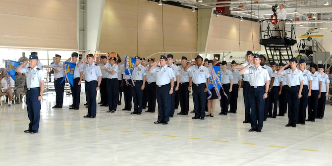 A formation of Airmen from the four squadrons of the 71st Mission Support Group render a welcoming salute to their new commander, Col. Thomas Gibson, during a change of command ceremony held July 17 in Hangar 199 at Vance AFB. Included in the salute were siren wails from Security Forces and fire department vehicles – and the enthusiastic barking of Roy, a military working dog. (U.S. Air Force photo/ Terry Wasson)