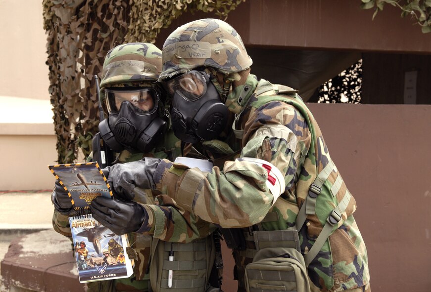 Senior Airman Leonardo Lingaolingao and Senior Airman Richard Rodriguez look in their Airman's Manual to identify an Unexploded Ordinanace outside the building during exercise Beverly Bulldog 09-03 at Osan Air Base, Republic of Korea. Airmen Lingaolingao and Rodriguez are entry controllers at the 51st Medical Group. (U.S. Air Force photo/Senior Airman Stephenie Wade)
