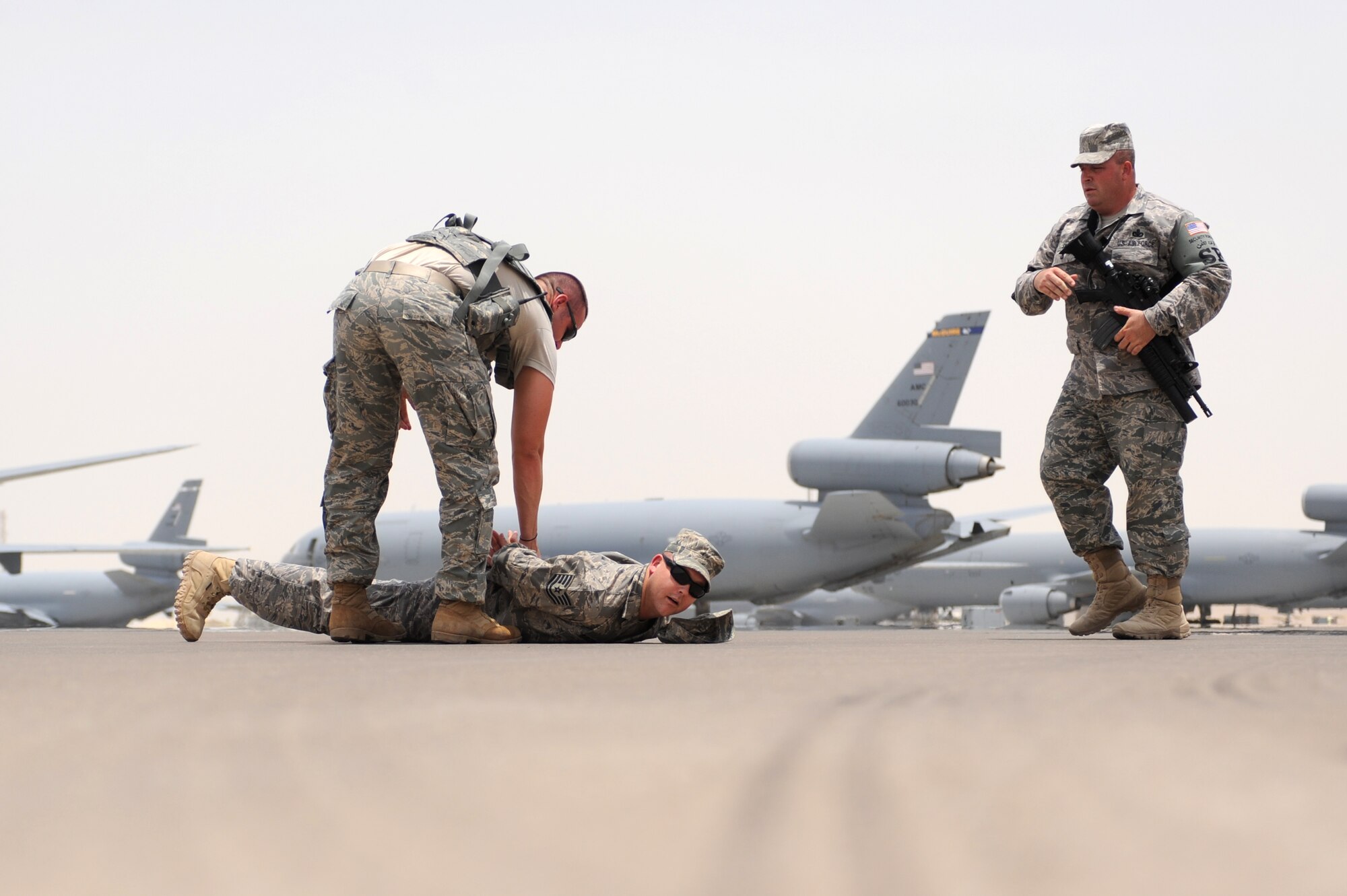 SOUTHWEST ASIA - Senior Airman Richard Franks, 380th Expeditionary Security Forces Squadron, demonstrates personnel apprehension on Tech. Sergeant Anthony Burleson, 380th Expeditionary Security Forces Squadron while Master Sergeant Mark Sapp stands as the over watch July 20. Airman Franks is deployed from Columbus Air Force base, Miss., and grew up in Hamilton, Ala. Sergeant Burleson is deployed from Tinker AFB, Okla., and hails from Sweetwater, Texas. Sergeant Sapp's home station is Edwards AFB, Calif., and he grew up in Dayton, Ohio. (U.S. Air Force photo Tech. Sgt. Charles Larkin Sr)