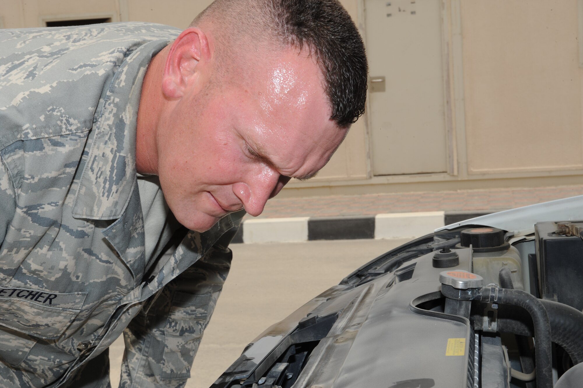 SOUTHWEST ASIA - Technical Sergeant Steven Fletcher, 380th Expeditionary Security Forces Squadron, closely inspects an engine compartment to train personnel how to thoroughly inspect vehicles July 20. Sergeant Fletcher is deployed from Tinker Air Force base, Okla., and grew up in Tyler, Texas. (U.S. Air Force photo Tech. Sgt. Charles Larkin Sr)