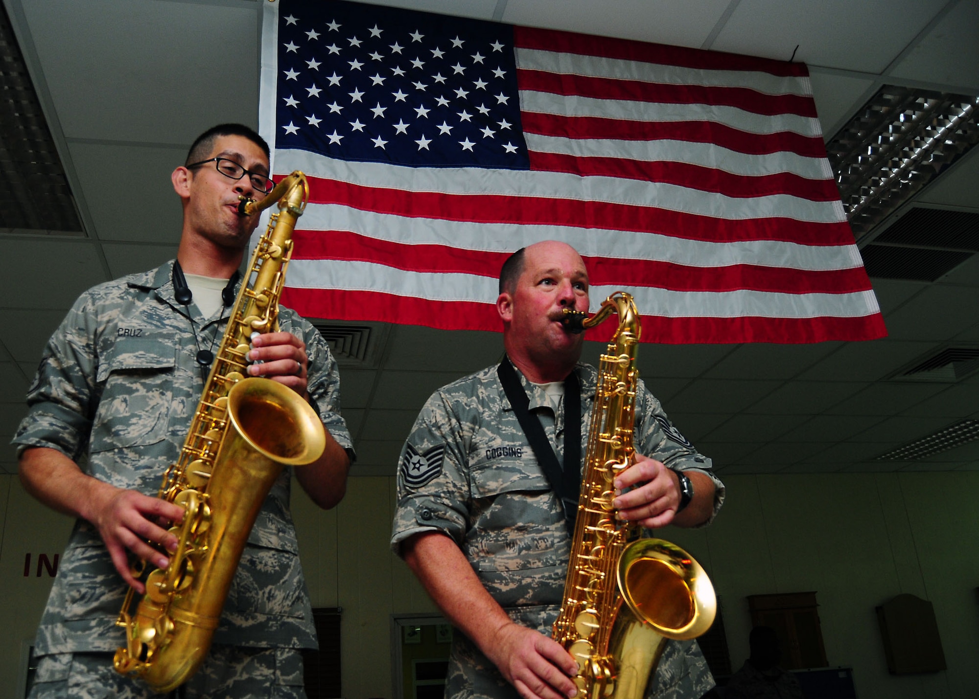 SOUTHWEST ASIA -- Staff Sgt. Jorge Cruz, left, and Brian Coggins, from the Air Force Central Command Sonora band, play saxaphone under the stars and stripes at a performance for the 386th Air Expeditionary Wing July 21. Sergeants Cruz and Coggins are members of the 129th Rescue Wing, Moffet Federal Air Field, Calif. (U.S. Air Force photo/Tony Tolley)
