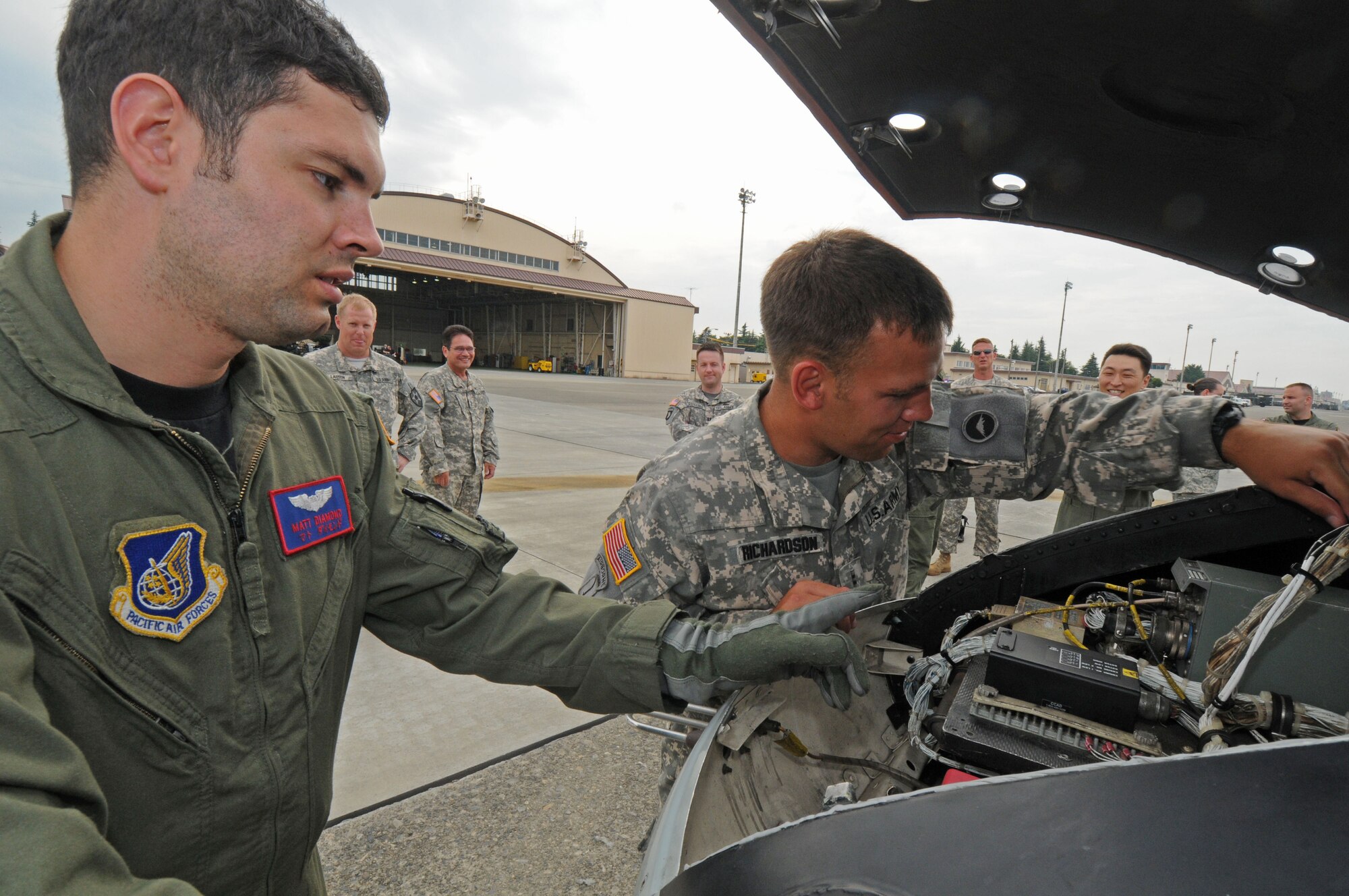 YOKOTA AIR BASE, Japan -- Army Warrant Officer Tony Richardson, 78th Aviation Company HH-60 pilot (right), and Air Force 1st Lt. Matthew Diamond, 459th Airlift Squadron UH-1N pilot, look at a Huey engine during a joint service training day July 17. Both the Air Force and Army play a crucial role in the airlift mission for the Pacific region. The 459th AS and 78th AC from Camp Zama came together to share their expertise and information on local area flying techniques. During the professional exchange the units learned about each other's regular flight routes, capabilities and experiences. (U.S. Air Force photo/Staff Sgt. Veronica Pierce)  
