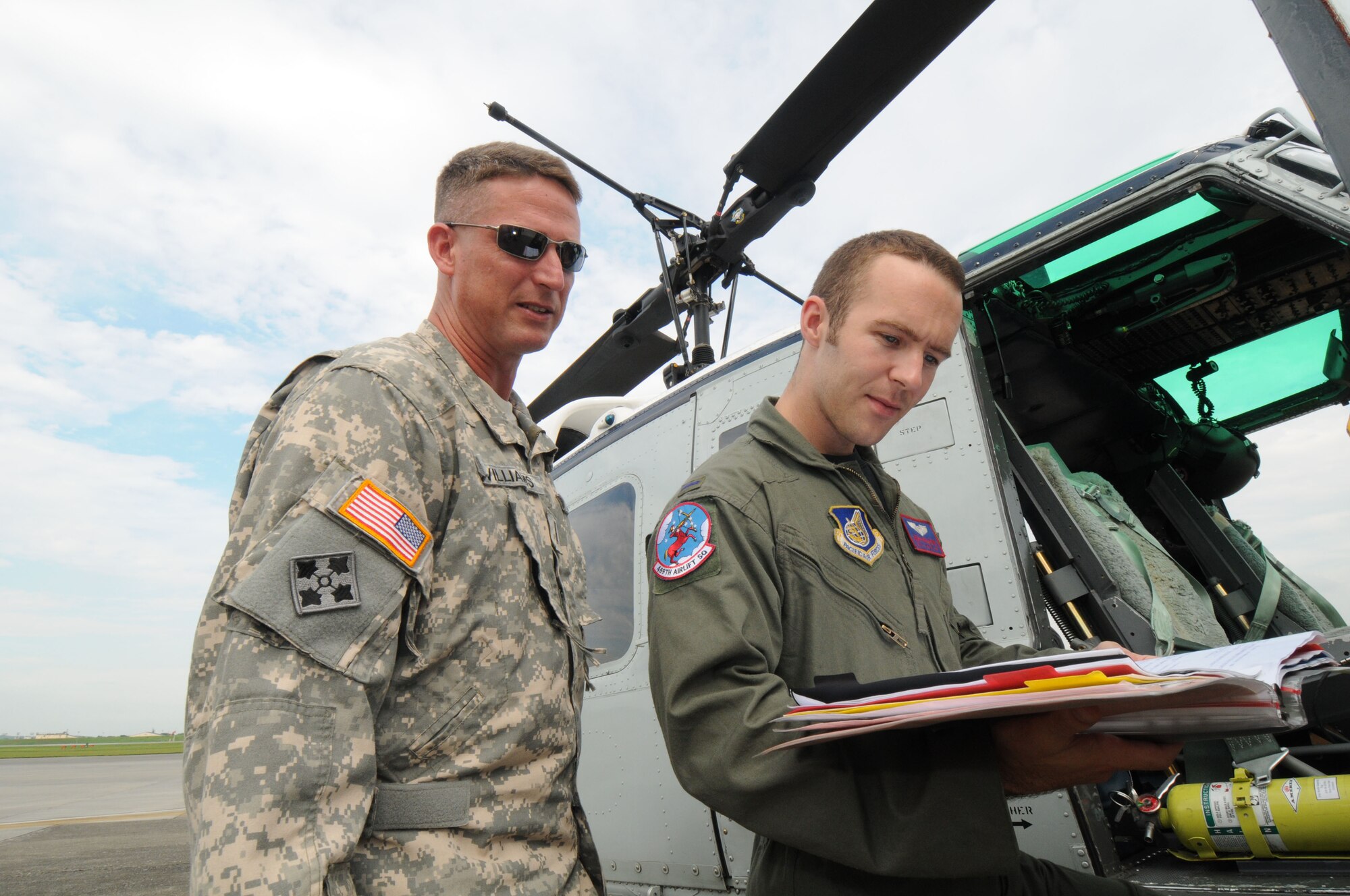 YOKOTA AIR BASE, Japan -- Army Warrant Officer Stephen Williams, 78th Aviation Company HH-60 blackhawk pilot (left), and Air Force 1st Lt. Josh Hallford, 459th Airlift Squadron UH-1N Huey pilot, read through Huey technical orders as part of a joint service training day July 17.  Both the Air Force and Army play a crucial role in the airlift mission for the Pacific region. The 459th AS and 78th AC from Camp Zama came together to share their expertise and information on local area flying techniques. During the professional exchange, the units learned about each other's regular flight routes, capabilities and experiences. (U.S. Air Force photo/Staff Sgt. Veronica Pierce)