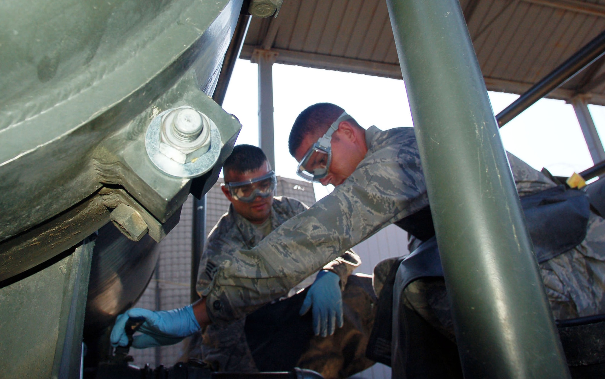 TRANSIT CENTER AT MANAS, Kyrgyzstan – Staff Sgt. Gregory Bailey and Senior Airman Samuel Wickersham, 376th Expeditionary Logistics Readiness Squadron’s petroleum, oil and lubricants Airmen, drain a fuel filter system through a valve to check jet fuel for foreign particles and contaminations at the Transit Center at Manas July 15, 2009. The POL team recently broke refueling records at Manas, after pumping over 10 million gallons. Sergeant Bailey and Airman Wickersham’s duty on a daily basis is to ensure jet fuel meets Air Force specifications by injecting three fuel enhancing chemicals, namely: Fuel System Icing Inhibitor, Corrosion Inhibitor and Static Dissipater Additive. The two Airmen are deployed from Aviano Air Base, Italy.  (U.S. Air Force photo/Staff Sgt. Olufemi Owolabi) 