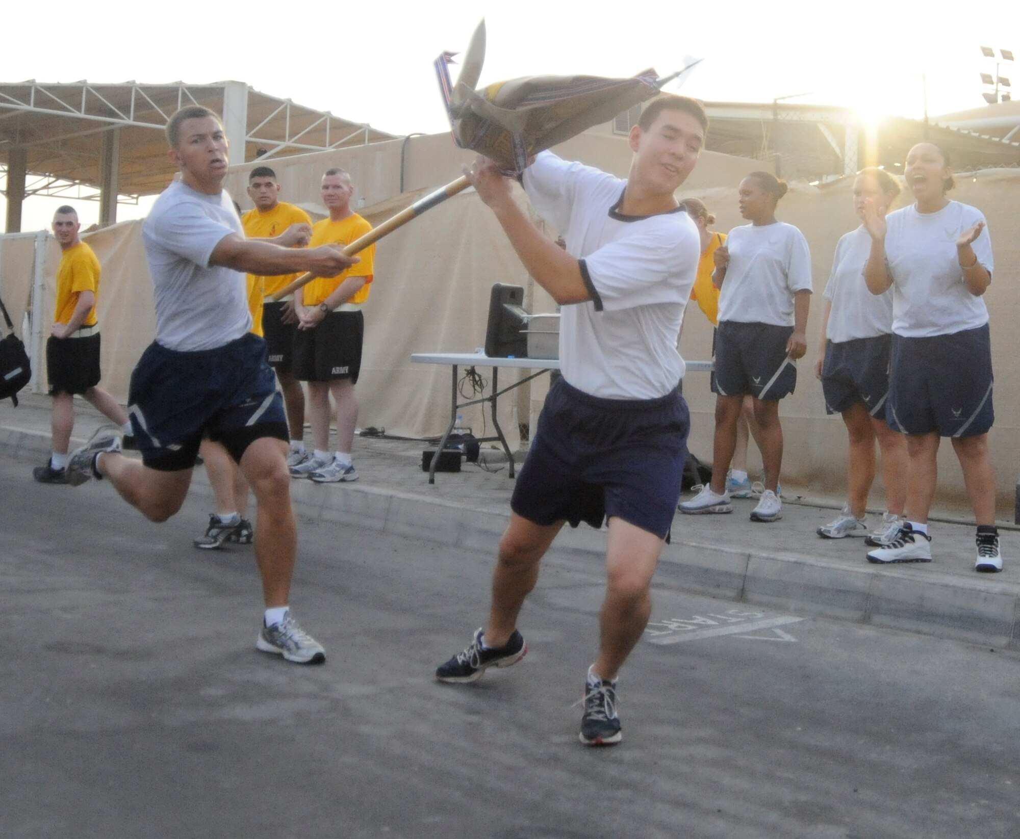 SOUTHWEST ASIA – Cadet 1st Class, Harold Parker, United States Air Force Academy takes the 380th Air Expeditionary Wing Guidon from Cadet 1st Class Ridge Flick, USAFA, as he begins the final lap here July 22. The Falcons took the lead in the seventh lap over the Soldiers and held onto it giving them the victory. Cadets Parker and Flick are seniors at the USAFA, Colo. Cadet Parker hails from Virginia Beach, Va., and Cadet Flick hails from Dallas, Texas. (U.S. Air Force photo/Senior Airman Stephen Linch)