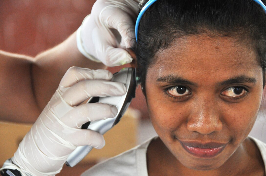 U.S. Air Force Senior Airman Ashley Cope checks an East Timorese woman's ear at a clinic in Dili, Timor Leste, July 16, 2009.