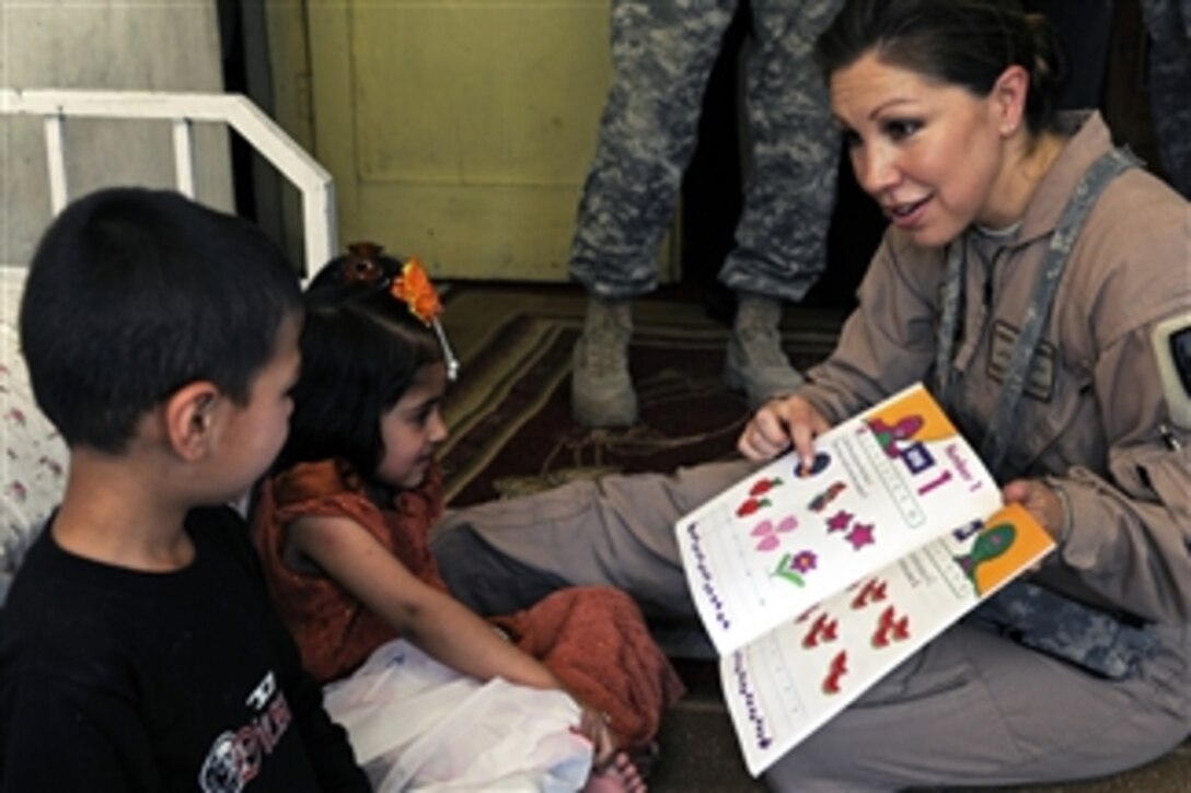 U.S. Air Force Master Sgt. Sarah Sparks, a Logistics Embedded Training Team integrator with Combined Security Transition Command -Afghanistan, shows a picture book to two Afghan children during a volunteer community relations visit at a day care center for the children of employees of the Afghan Geodesy and Cartography Head Office in Kabul, Afghanistan, on July 16, 2009.  