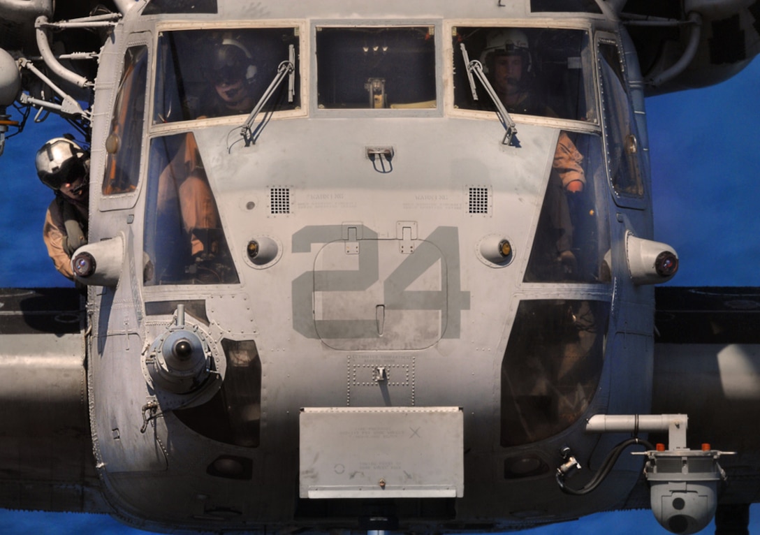 A crew chief peers out the side of a CH-53 Super Stallion helicopter as the pilot slowly lowers the helicopter to the flight deck of USS Bonhomme Richard July 22.